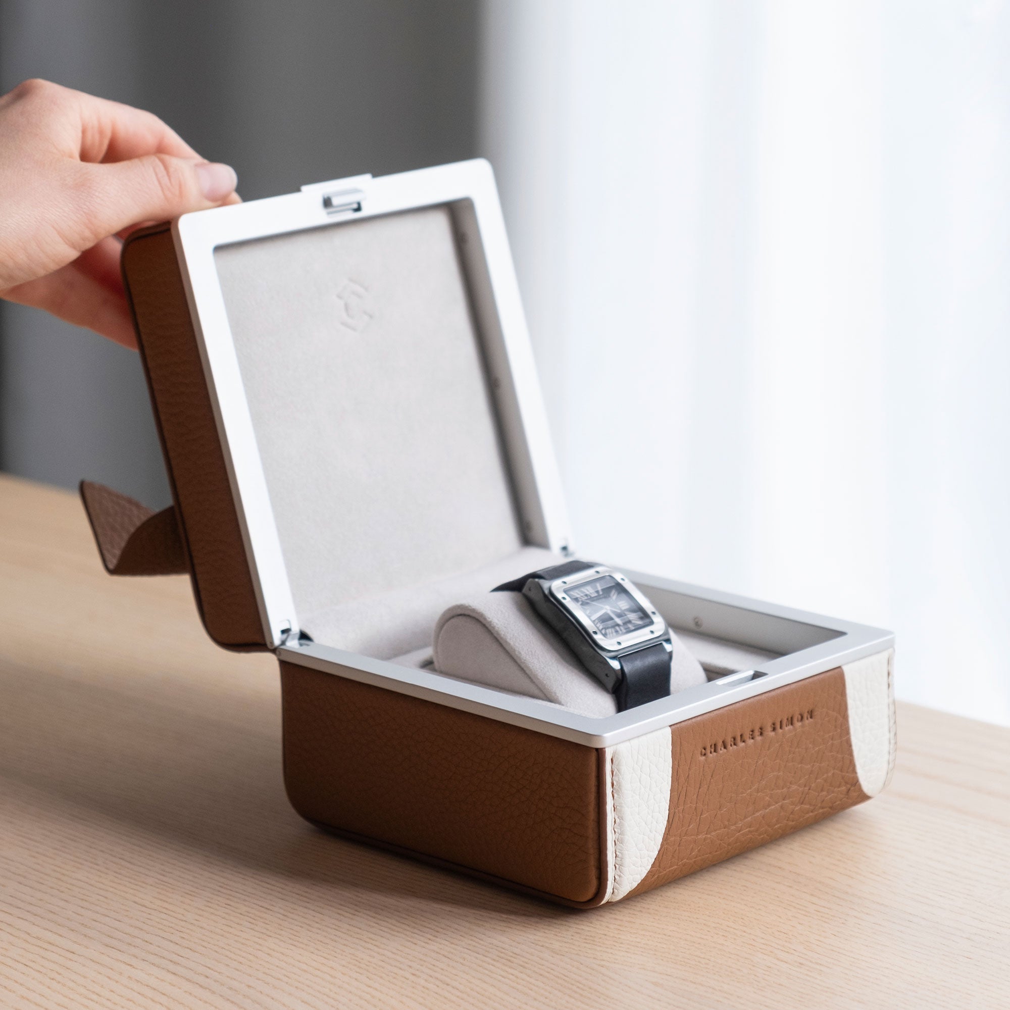 Lifestyle photo of hand opening Bulldog Eaton 1 special edition watch case showcasing the adorable dog design handmade from French leather. The watch case is storing one watch on a white watch cushion.