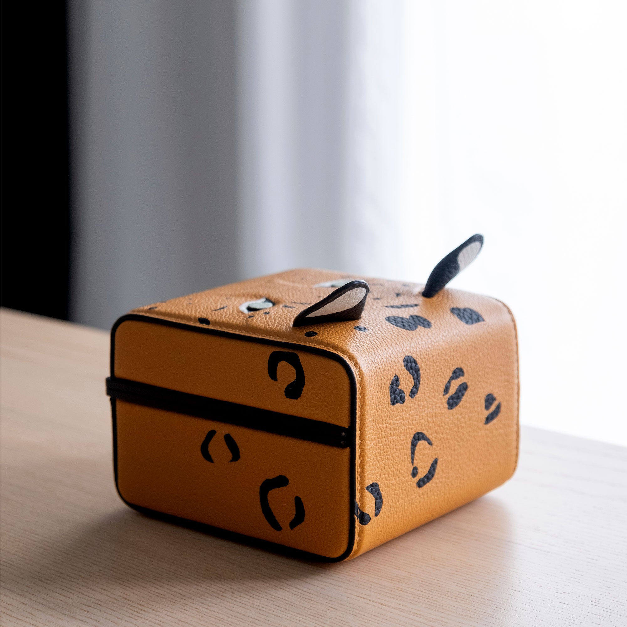 Lifestyle photo of back of the Eaton 1 Leopard Watch Case showcasing intricate leather working details and leopard print pattern. Handcrafted from premium French leather, soft Alcantara and black anodized aluminum casing.