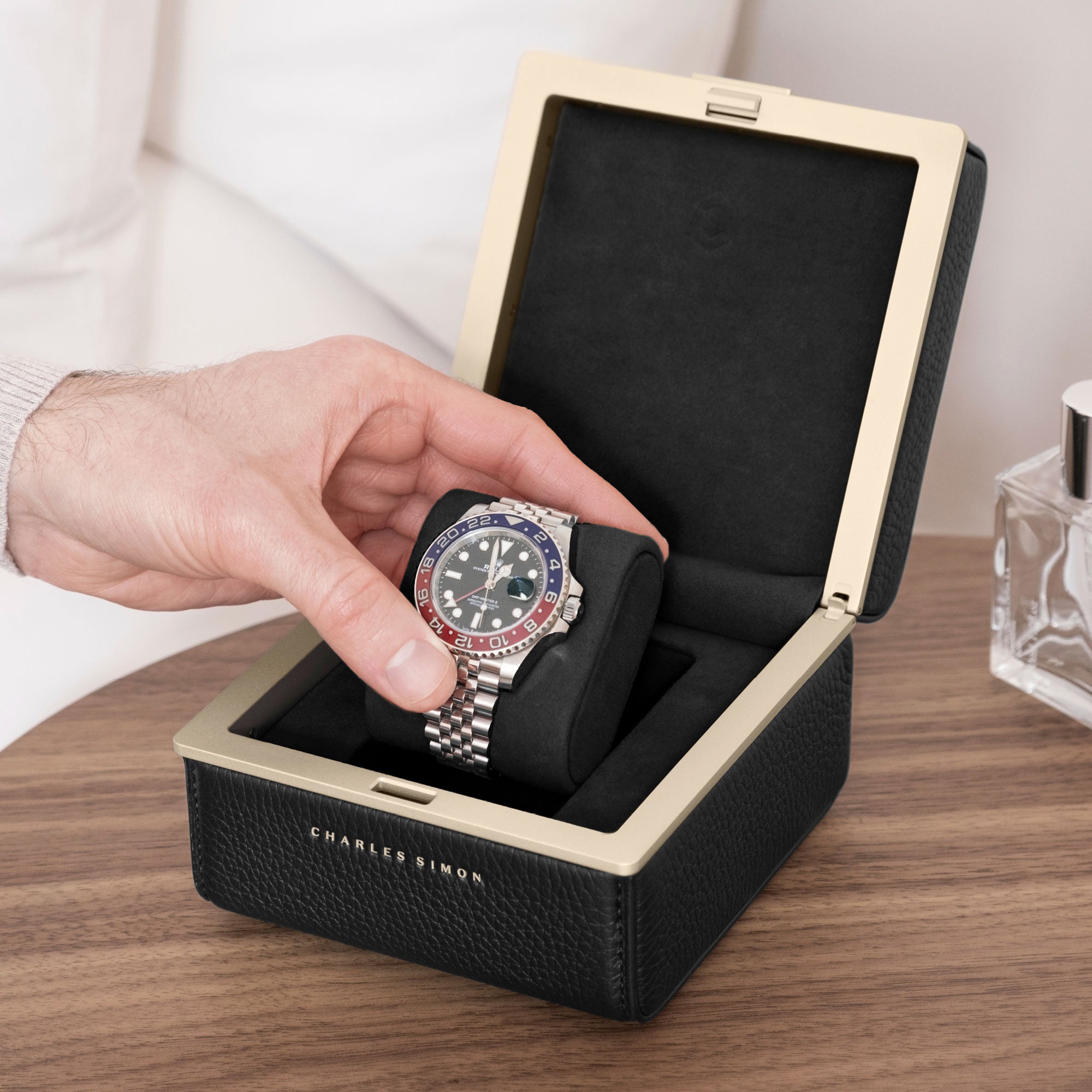 Man taking his luxury watch from the removable black cushion of the gold Eaton 1 watch case by Charles Simon.