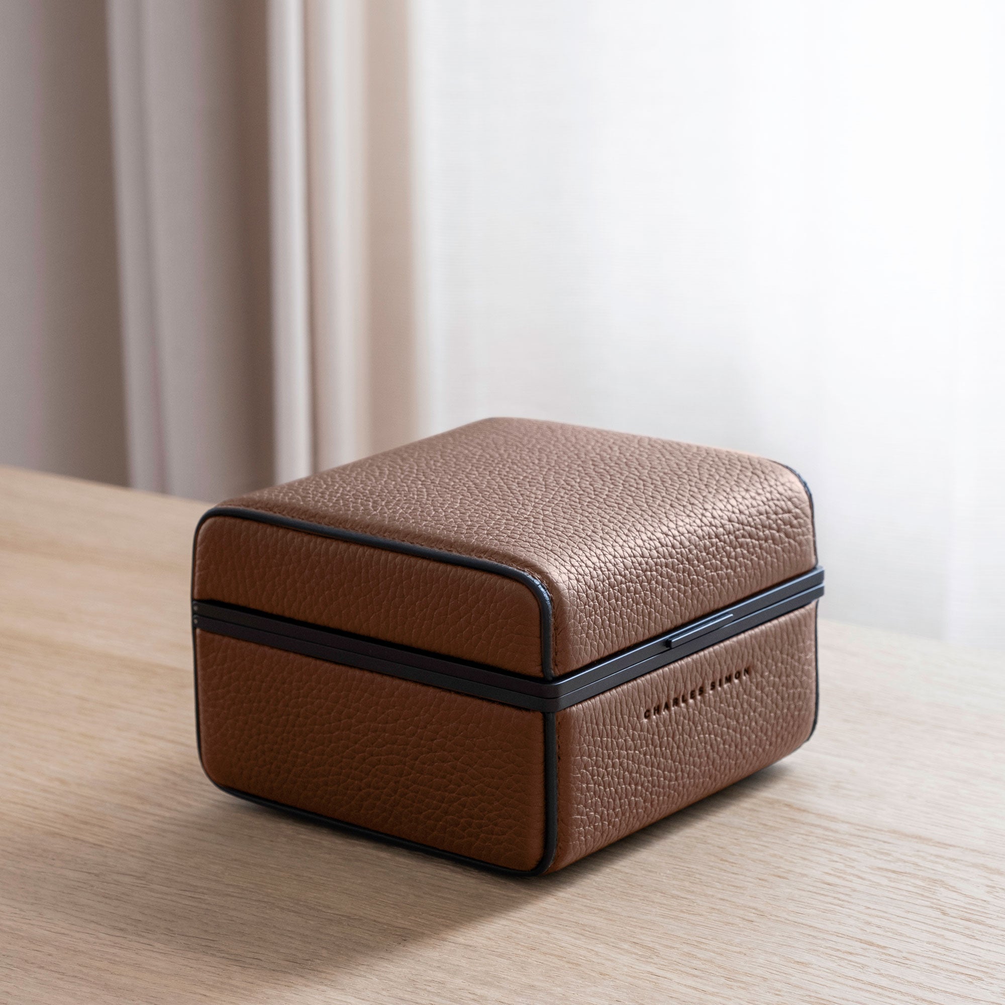 Lifestyle photo of closed Eaton 1 Watch case in tan leather and black anodized aluminum