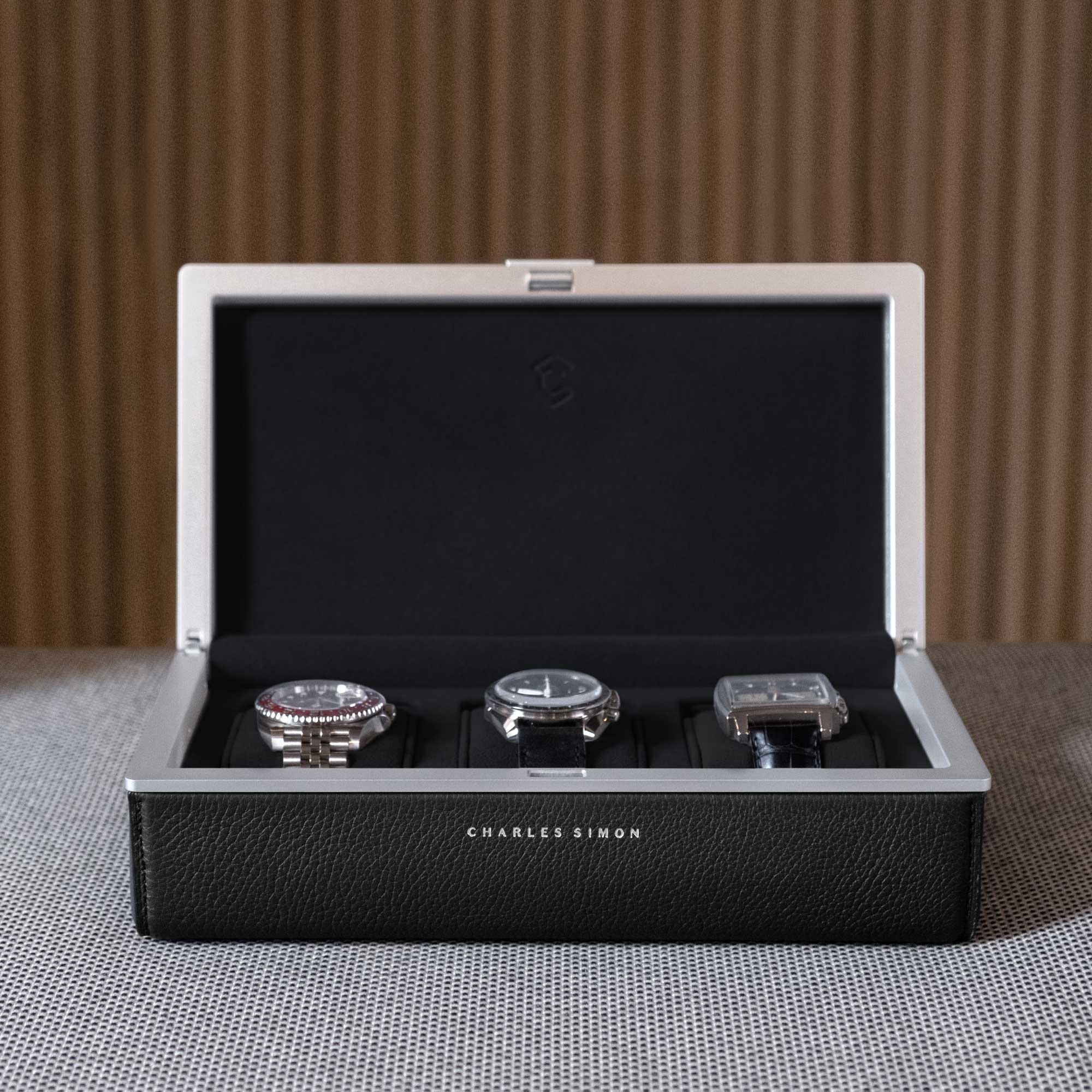 Front shot of open Eaton 3 watch case in black leather and grey anodized aluminum casing holding 3 men's luxury watches