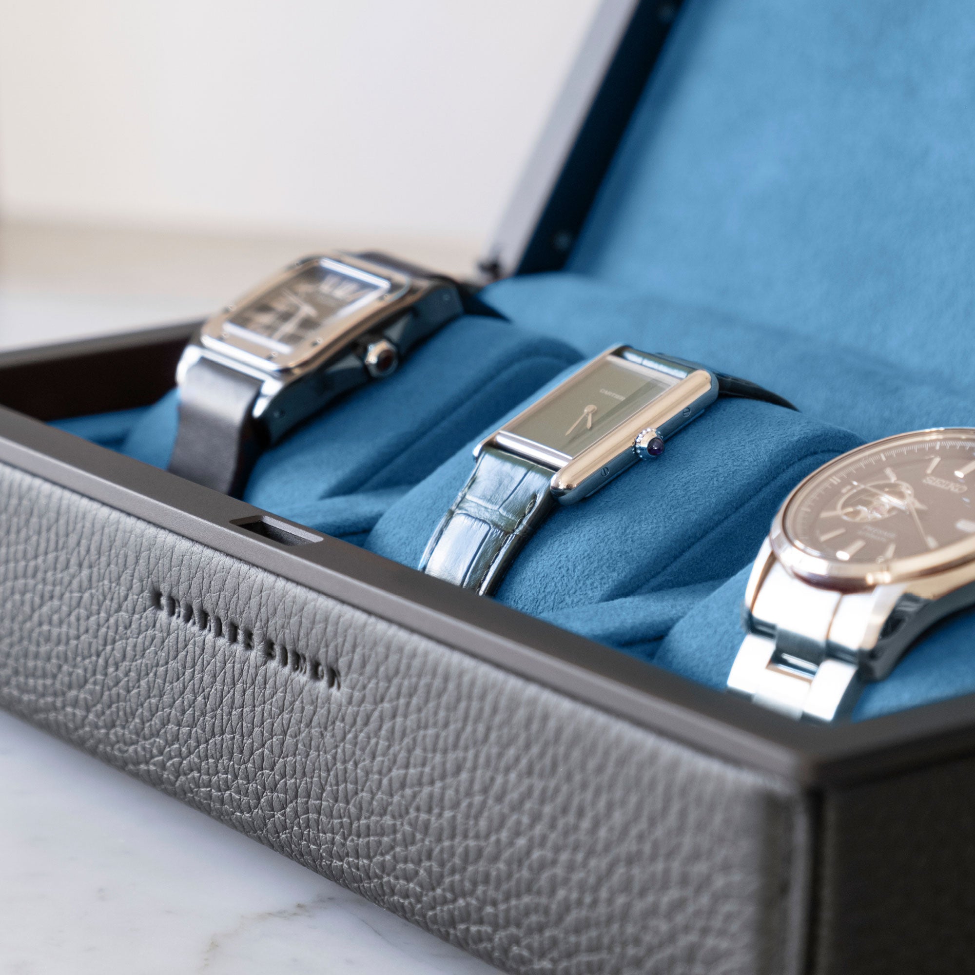 Closeup shot of Eaton 3 Watch case in black leather and soft cyan blue Alcantara interior holding 3 luxury watches including Cartier