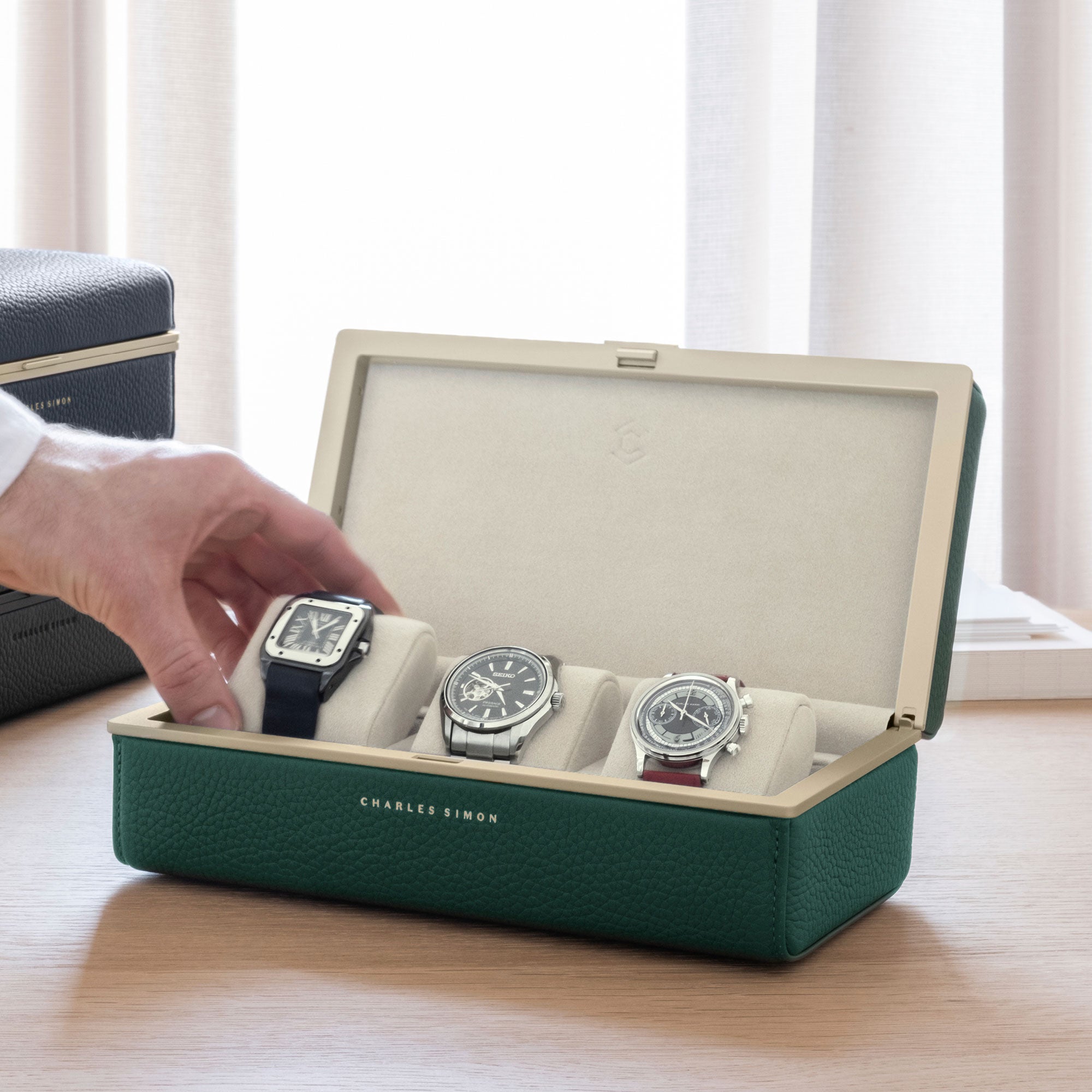 Man taking Cartier watch from eggshell cushion of the Eaton 3 Watch case in gold emerald leather