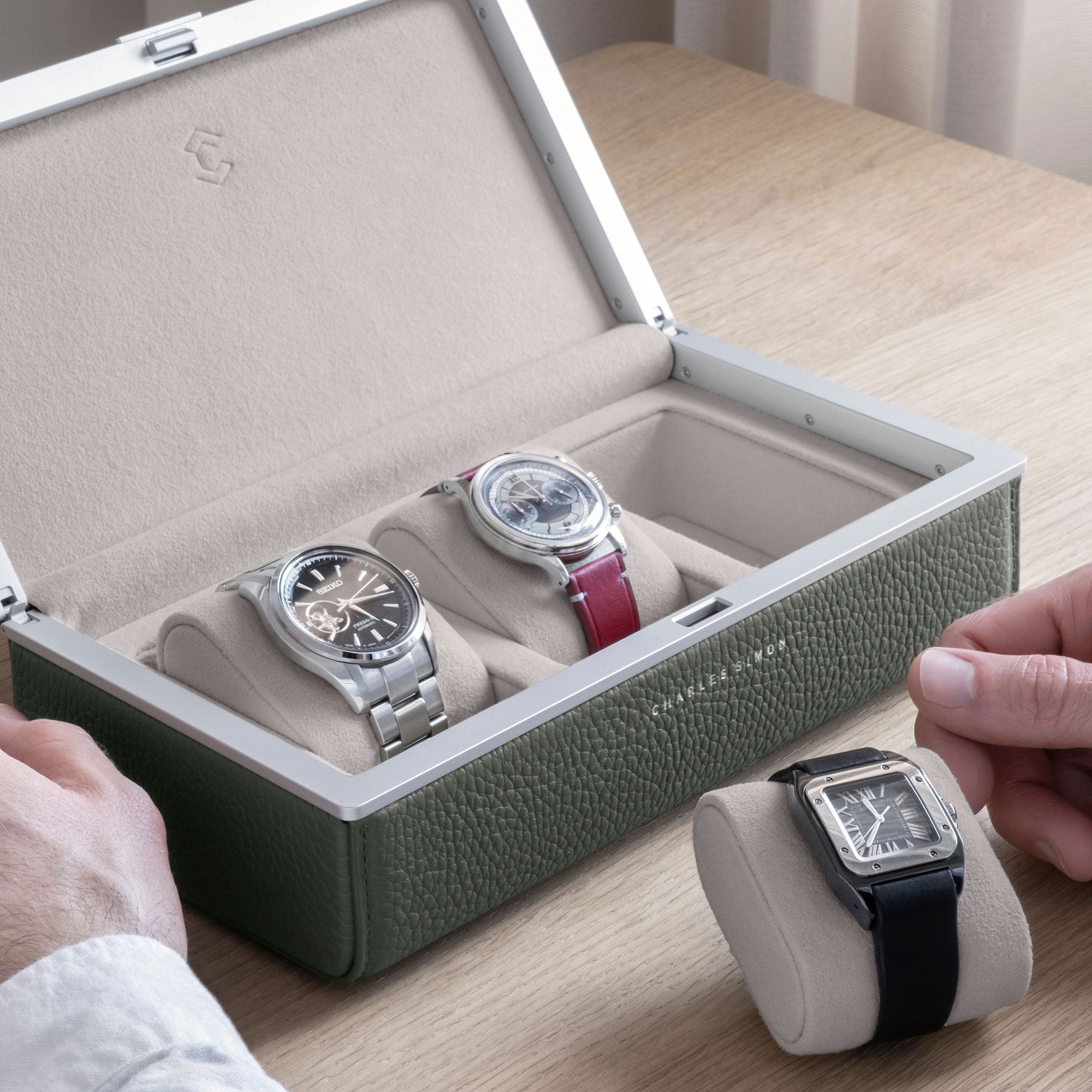 Lifestyle shot of Cartier watch placed on seasand Alcantara cushion in front of the Eaton 3 watch case for up to 3 watches