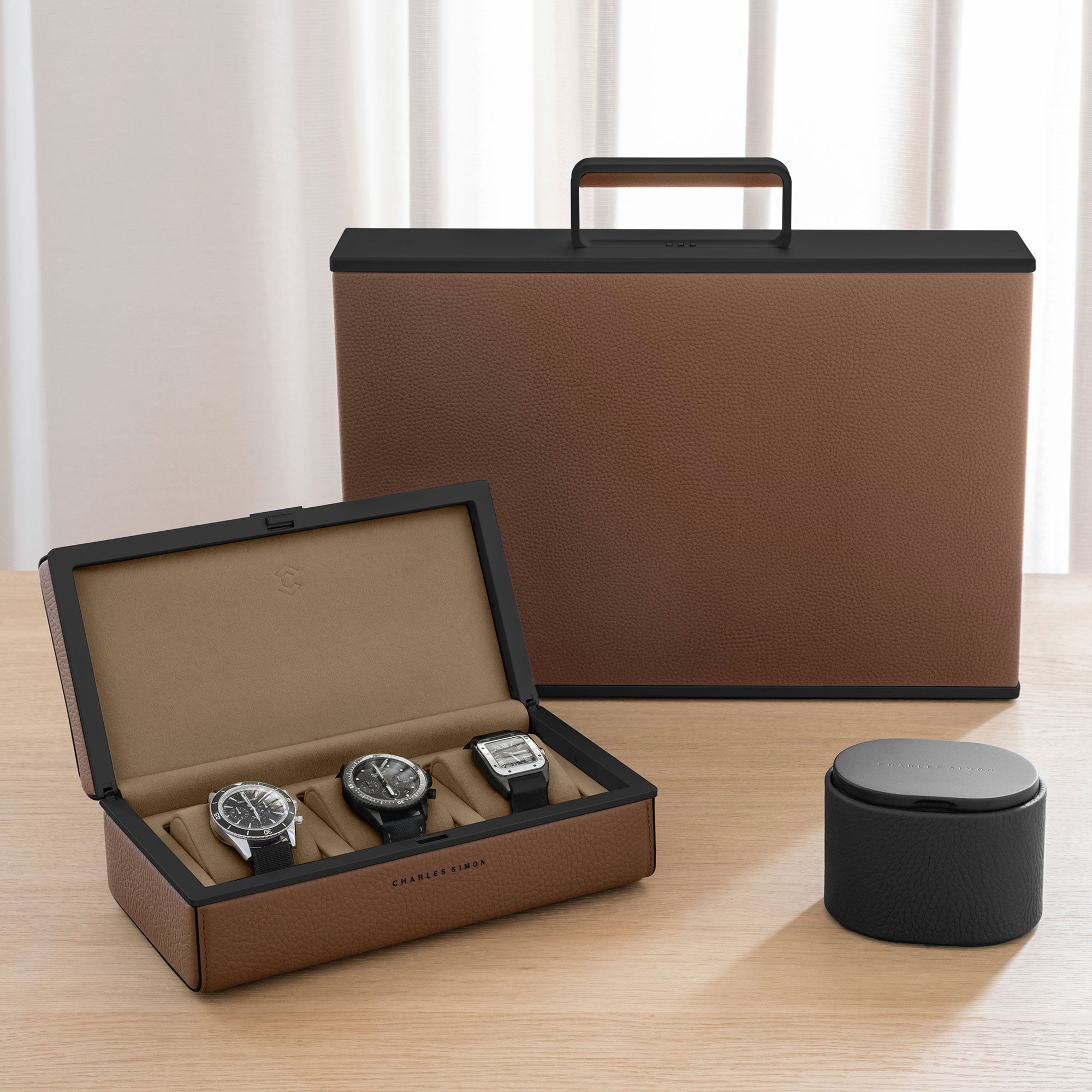 Charles Simon watch accessory collection, including Eaton 3 for 3 watches on the left, Theo watch roll on the right and Mackenzie Watch briefcase for a watch collection of up to 12 watches in tan leather, black carbon fiber and anodized aluminum and camel interior