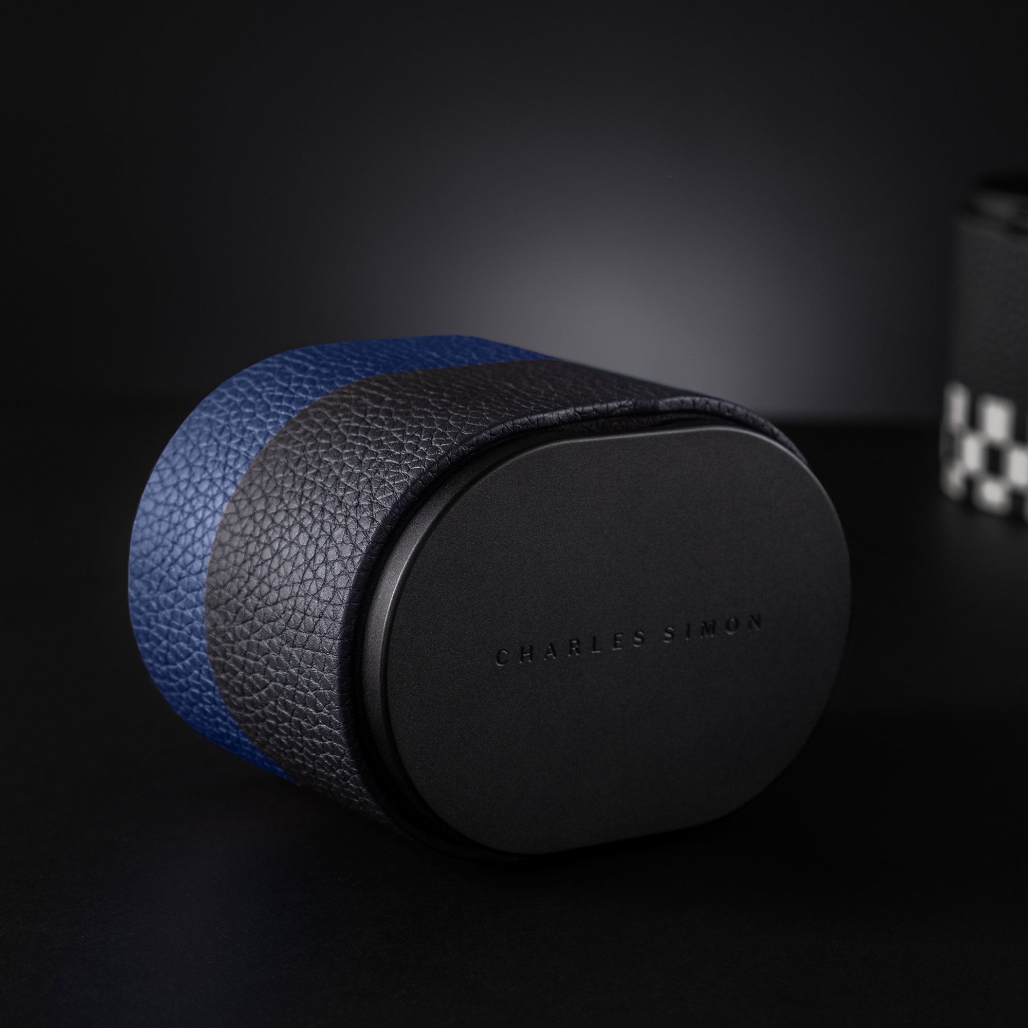 Lifestyle photo of black and blue leather watch roll by Charles Simon in front of a black background.