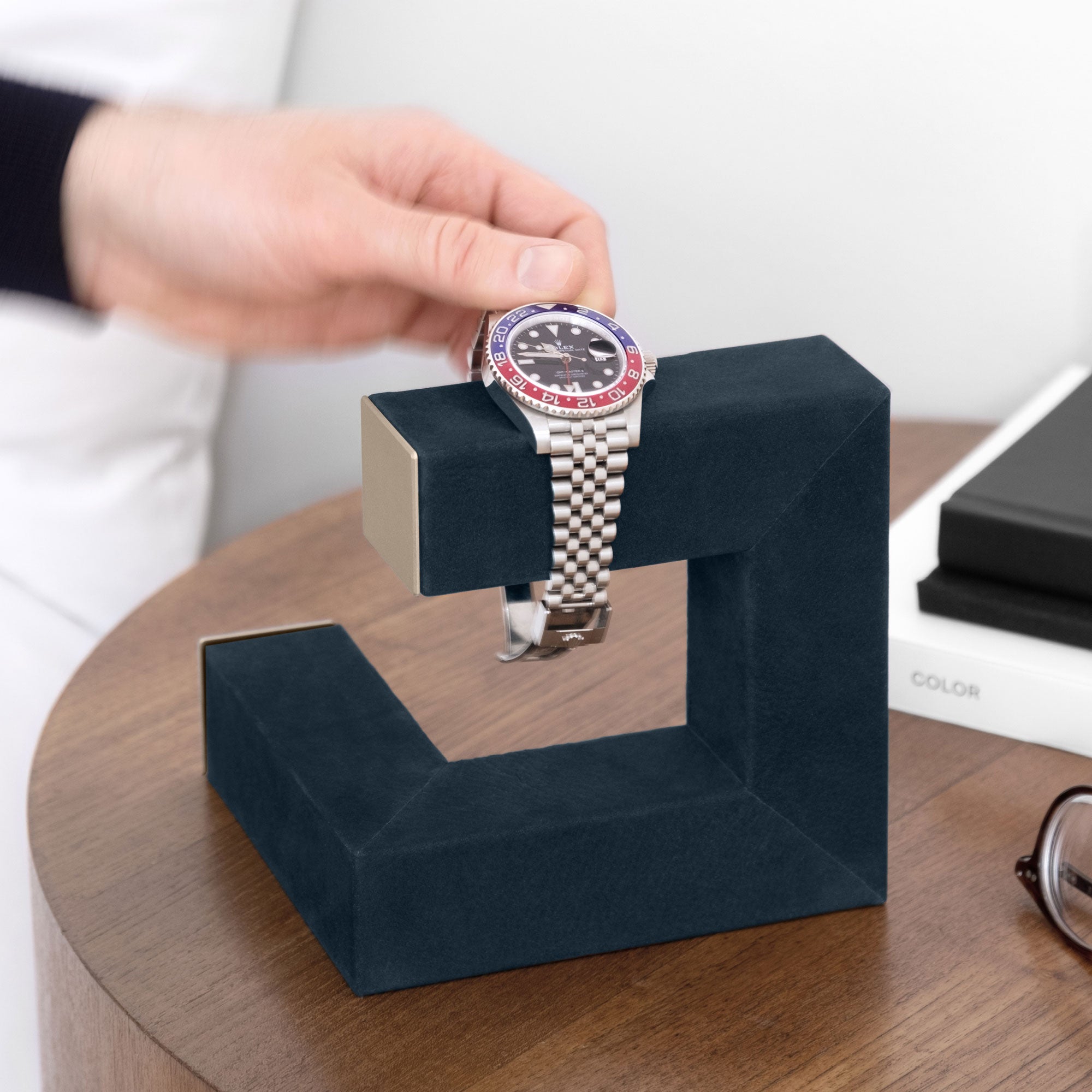 Man taking his Rolex from his gold watch stand.