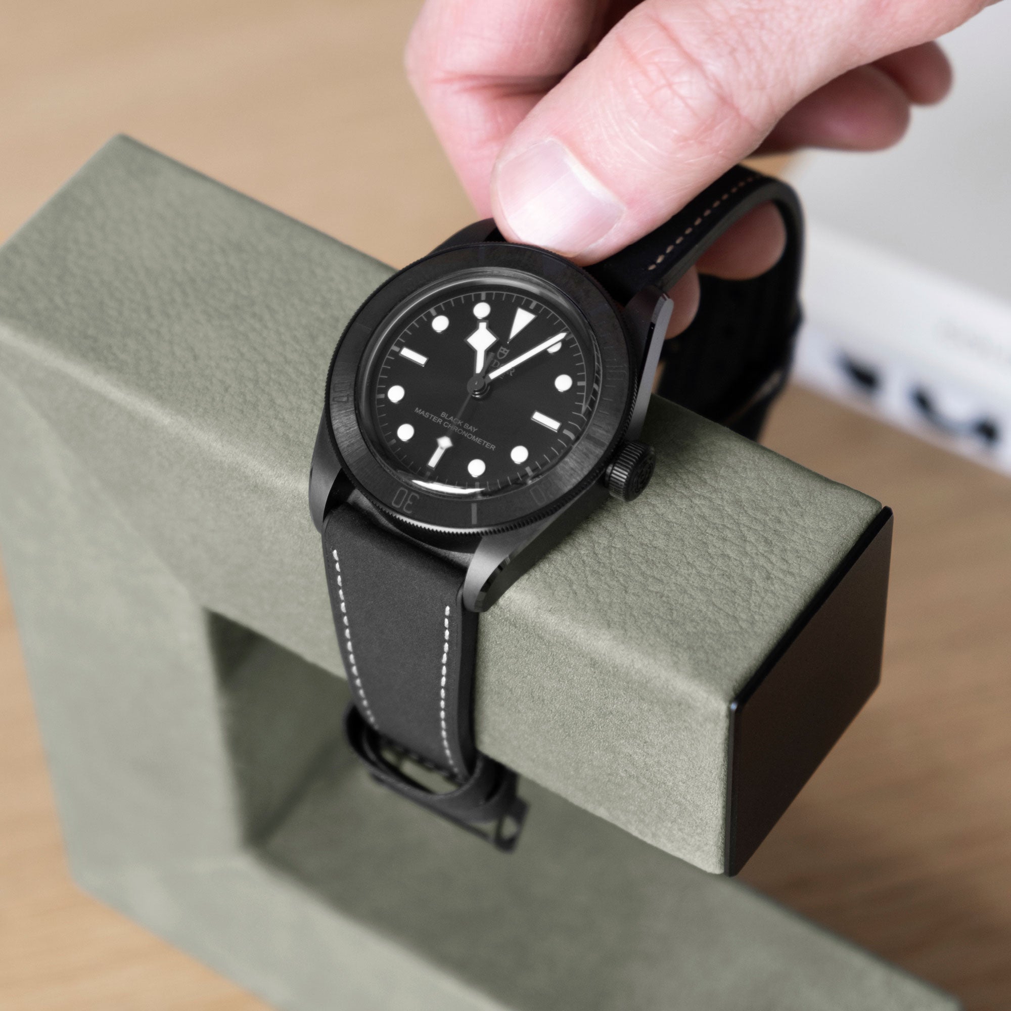 Luxury watch being taken off of Hudson 1 watch stand in sage