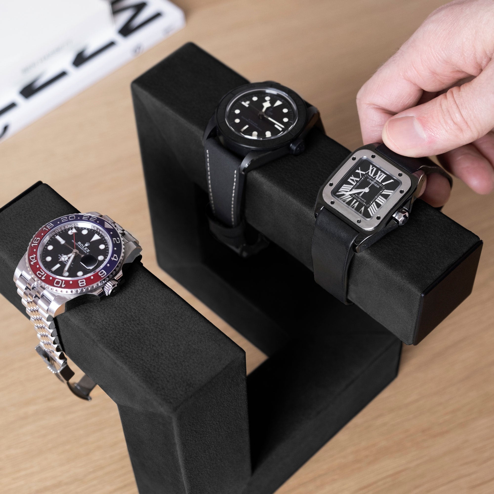 Lifestyle photo of man taking his luxury watch from the Hudson 3 Watch stand in all black
