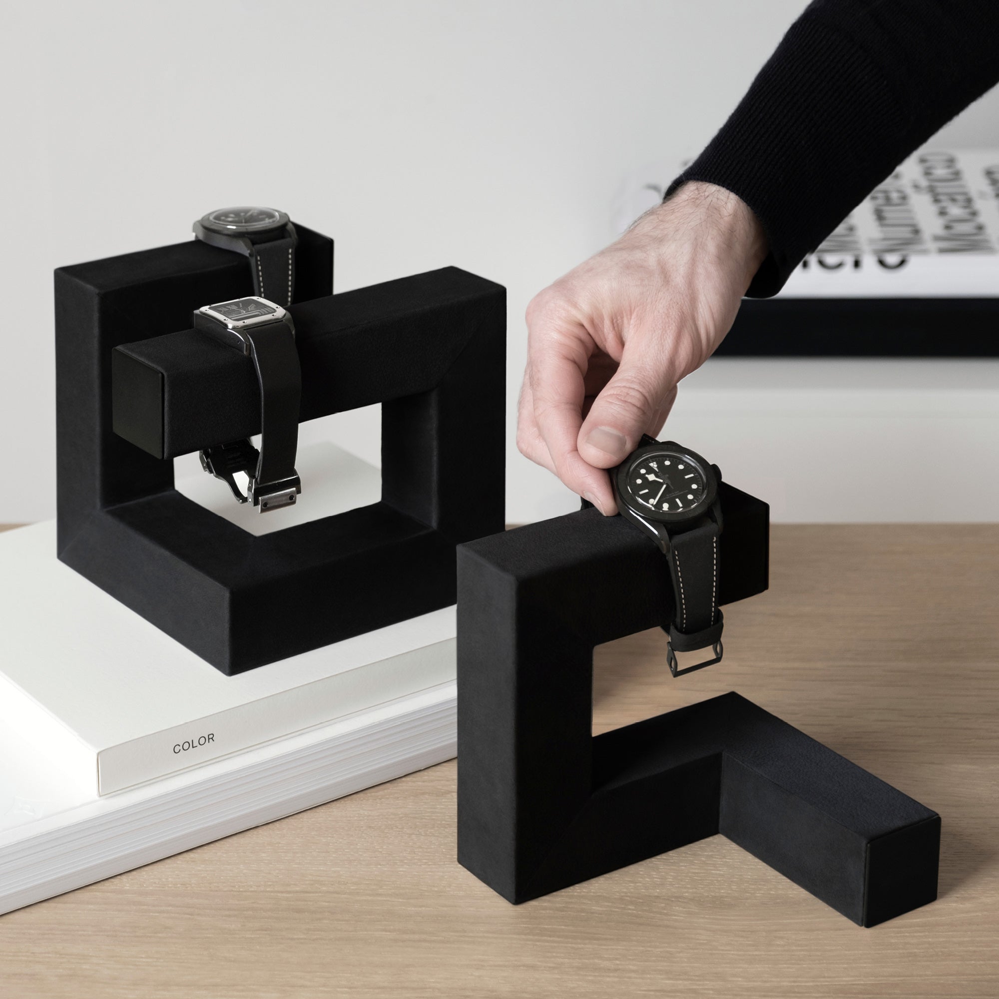 Gentleman taking watch from all black Hudson 3 watch stand in modern minimalist home