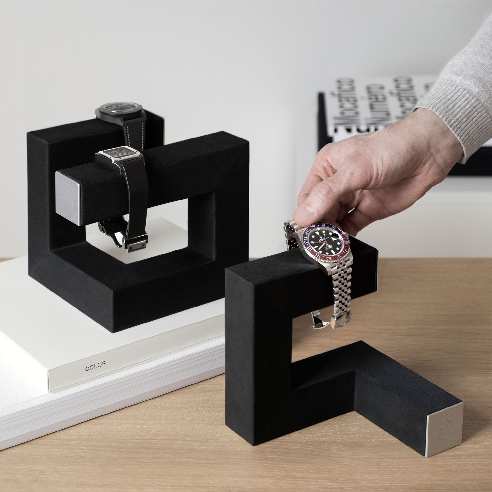 Man taking his Rolex from his Hudson 1 watch stand while his Hudson 3 Watch stand is displaying two more watches in the back