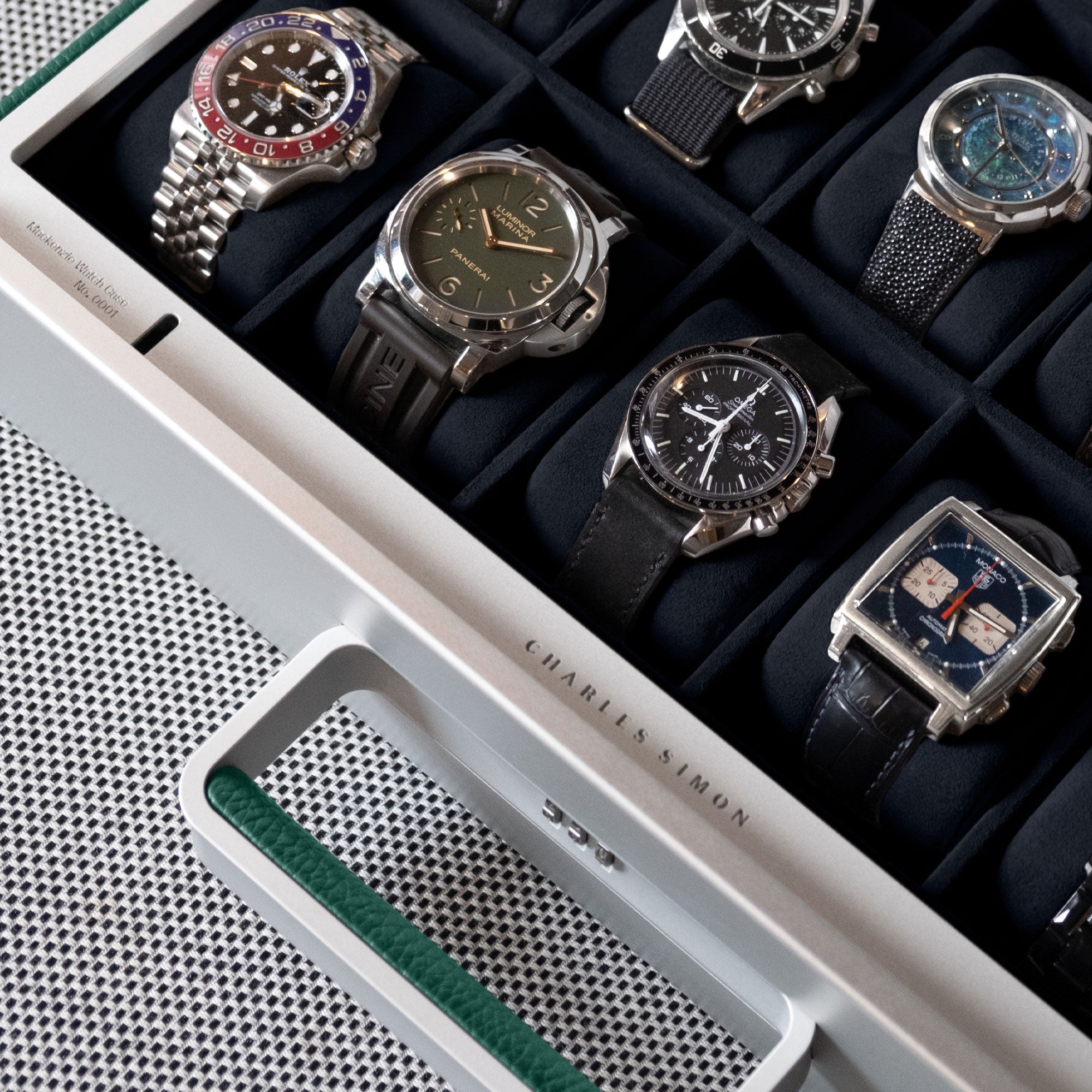 Lifestyle shot of emerald leather Mackenzie 10 watch briefcase filled with luxury men's watches including Rolex, Panerai and Omega. 