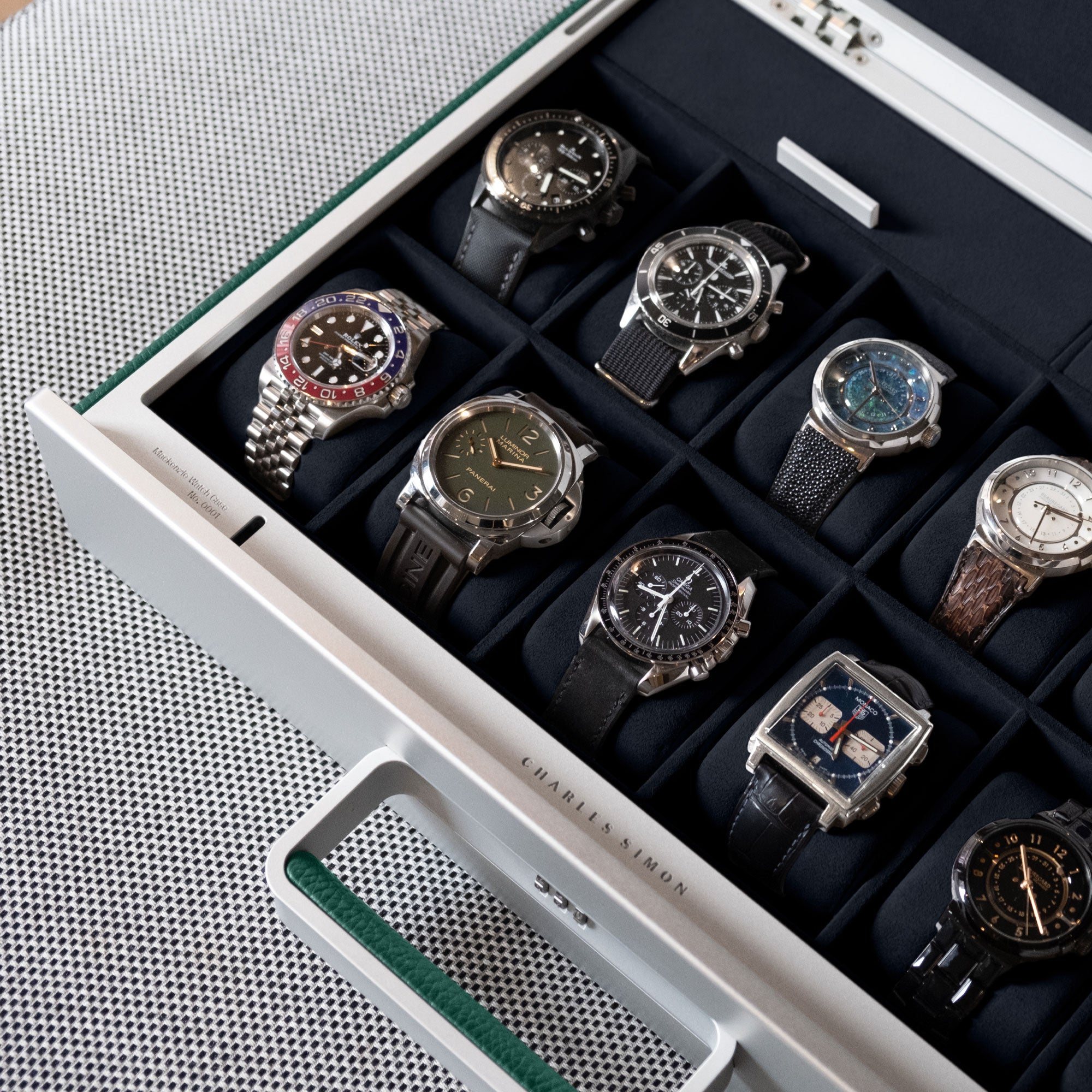Lifestyle shot of emerald Mackenzie watch briefcase filled with luxury watches including Rolex, Panerai and Omega