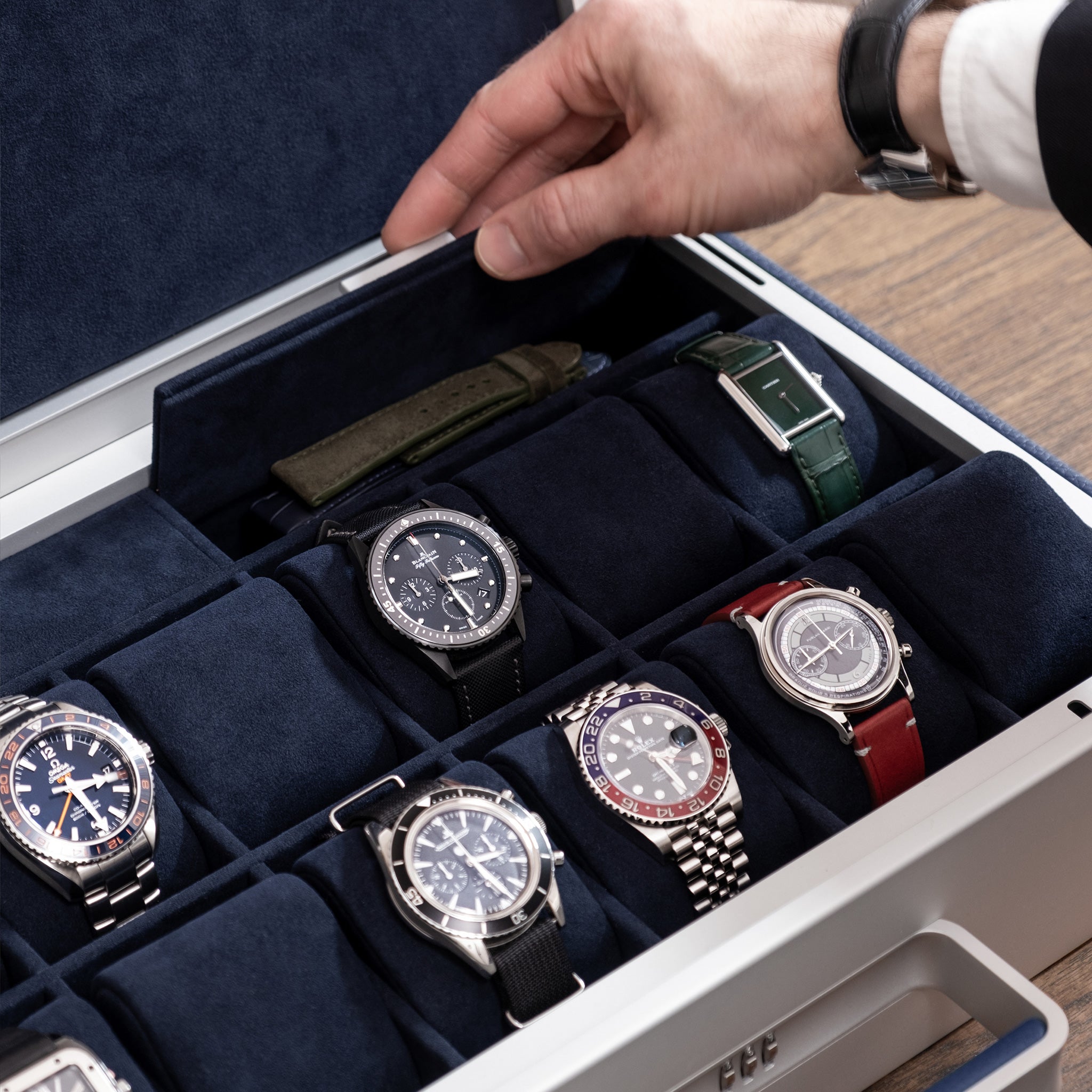 Lifestyle photo of man opening storage compartment of the Mackenzie 12 luxury watch briefcase in sapphire leather and deep blue Alcantara containing watch straps and other watch accessories