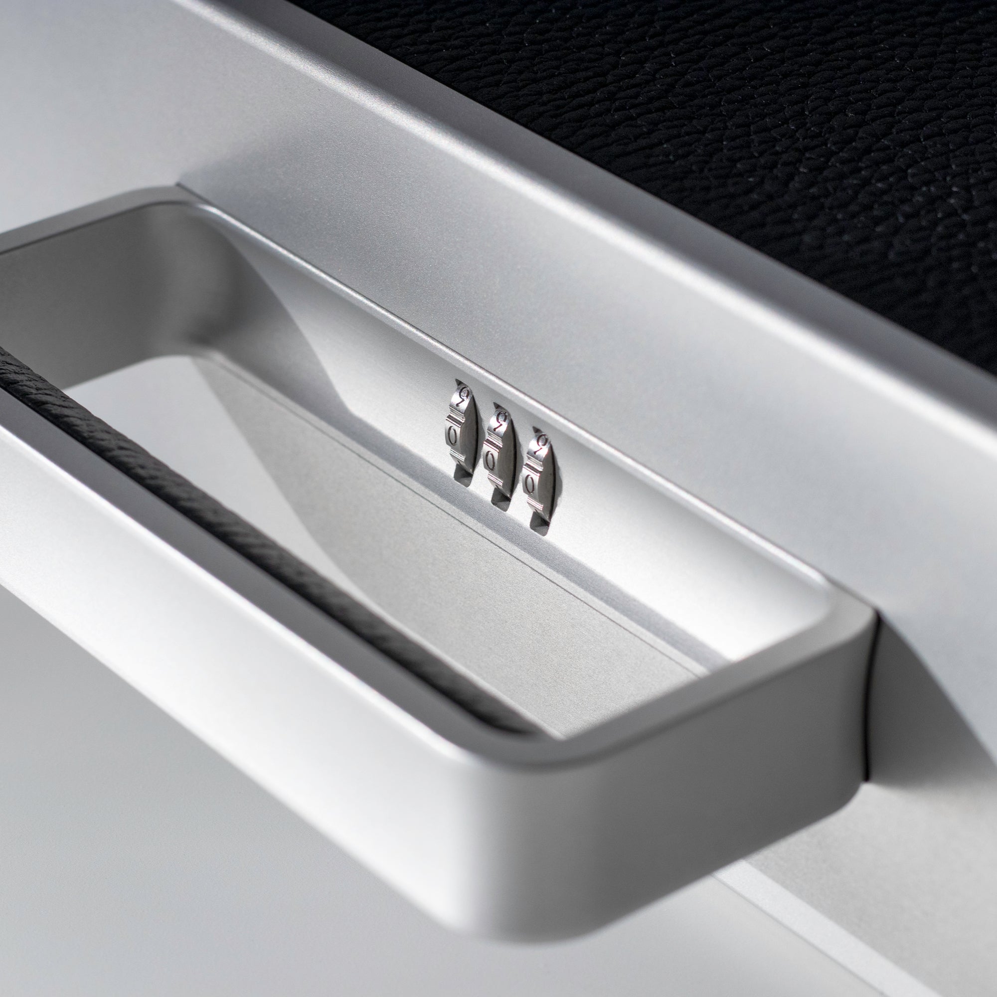 Closeup shot of Mackenzie 10 watch case in black leather showcasing sleek grey aluminum handle and lock with personalized code