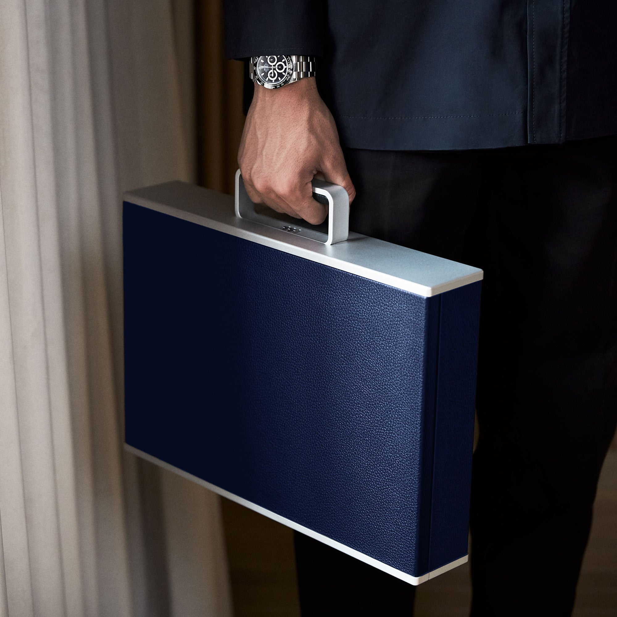 Man holding his sapphire leather Mackenzie Briefcase while wearing a luxurious watch