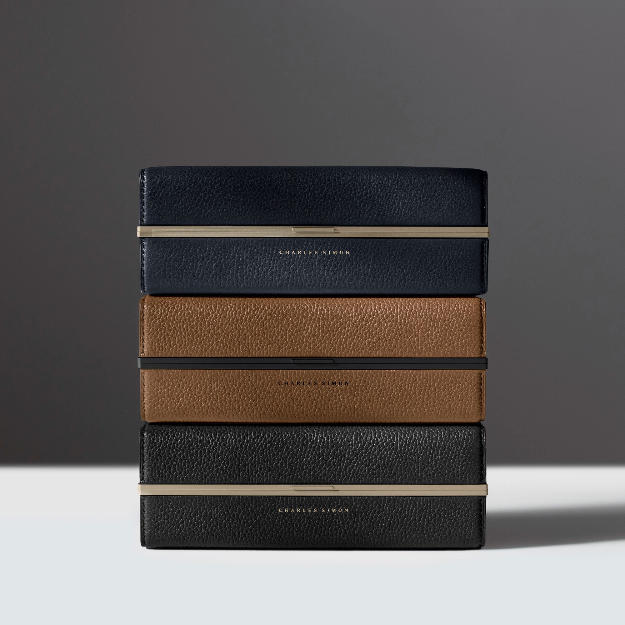 Lifestyle photo of three stacked minimalist toiletry cases by Charles Simon.