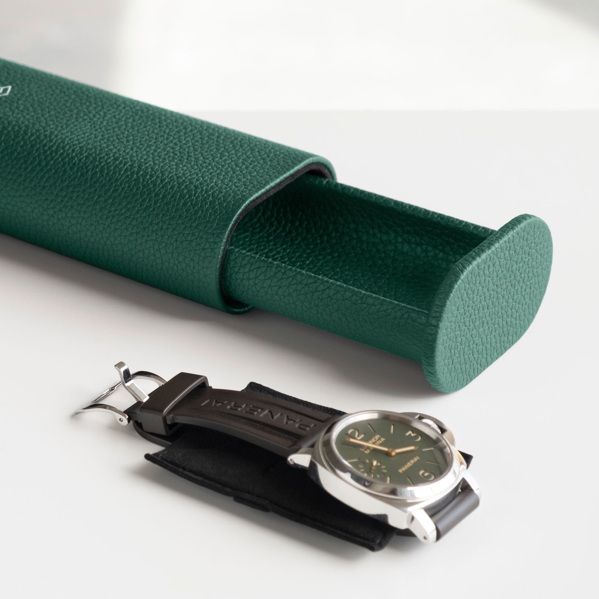 Open emerald leather Oscar Tall travel watch roll with men's luxury watch placed on Alcantara card insert in the foreground