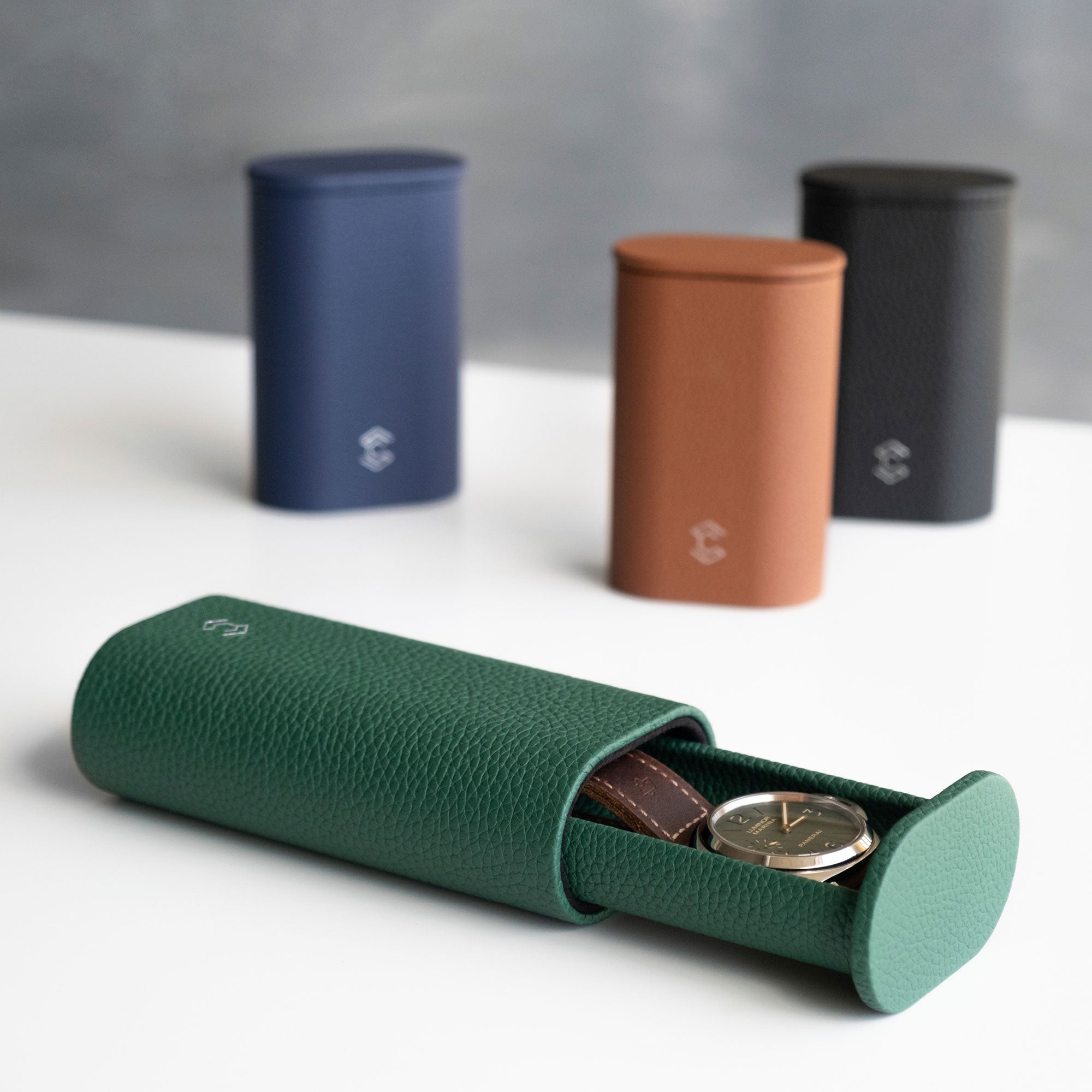 Lifestyle photo of open emerald leather Oscar 1 Tall Watch roll holding a men's watch with a leather strap