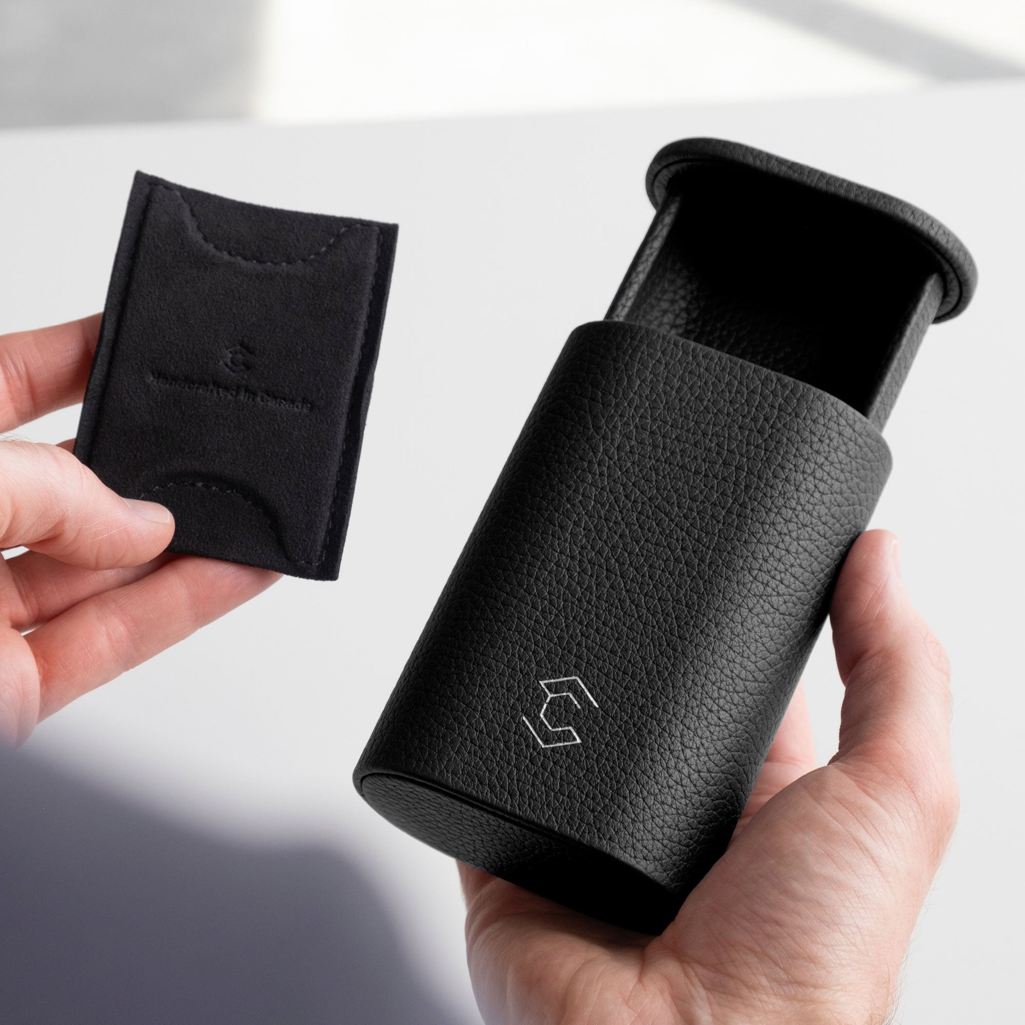 Man holding black leather Oscar Watch roll in one hand and the card insert to hold the watch in place in the other hand.