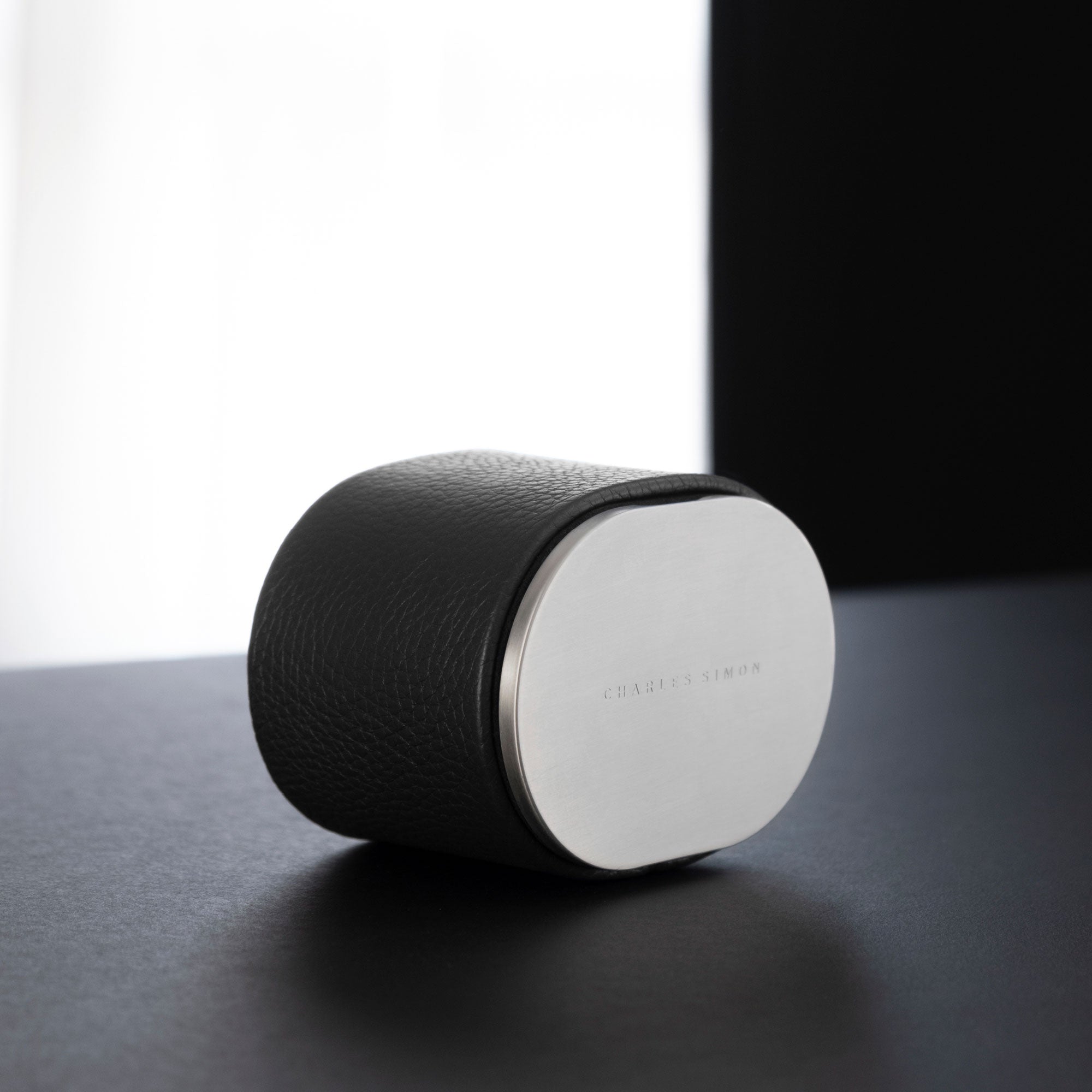 Lifestyle photo of closed Theo travel watch roll for 1 watch in black leather and grey aluminum