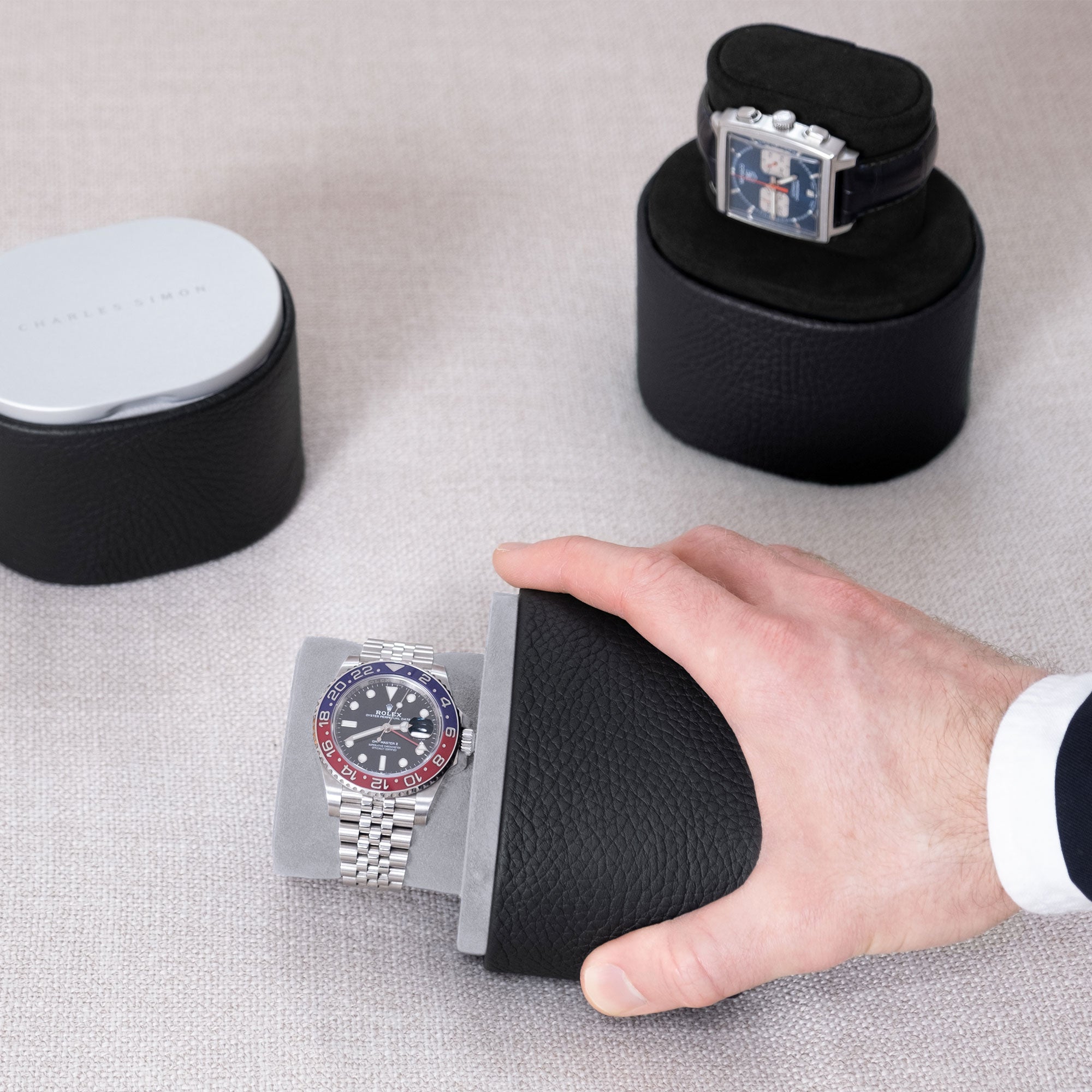 Lifestyle shot of 3 designer Theo travel watch rolls in black leather. Handmade to display and transport one watch