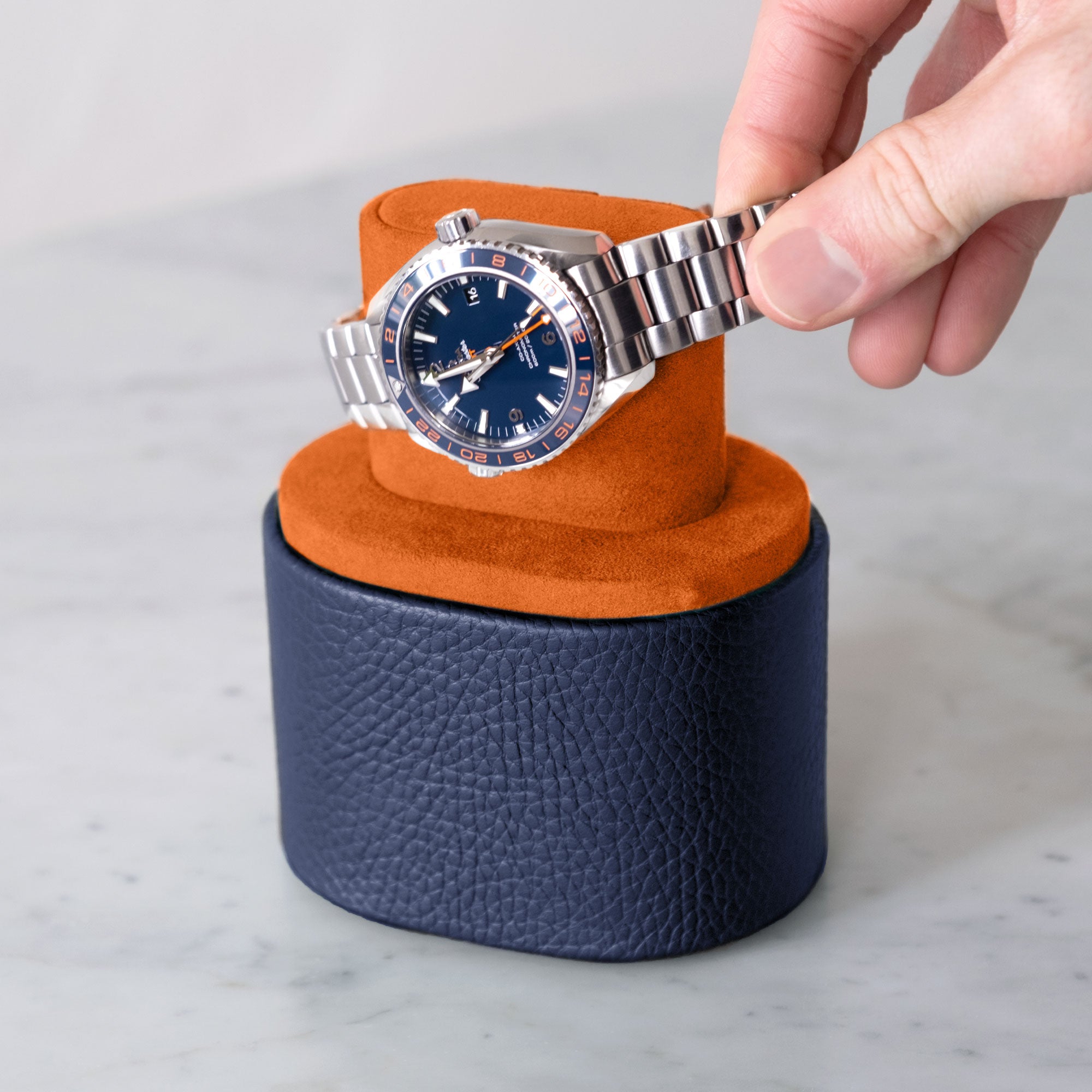 Lifestyle photo of man taking luxury watch from Theo Leather Watch roll in sapphire exterior and papayaa Alcantara.