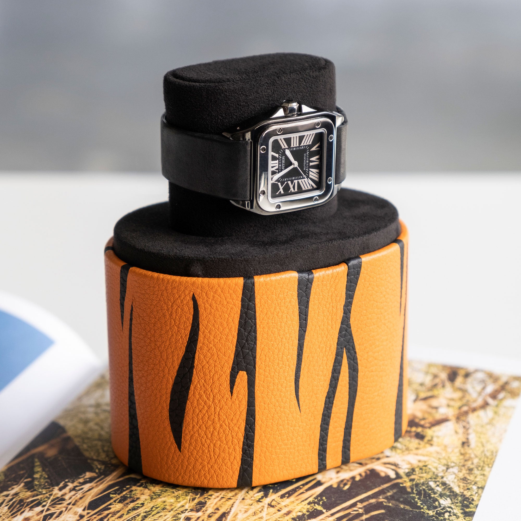 Cartier Watch placed on stylish tiger watch roll by Charles Simon showcasing double functionality as a portable watch stand