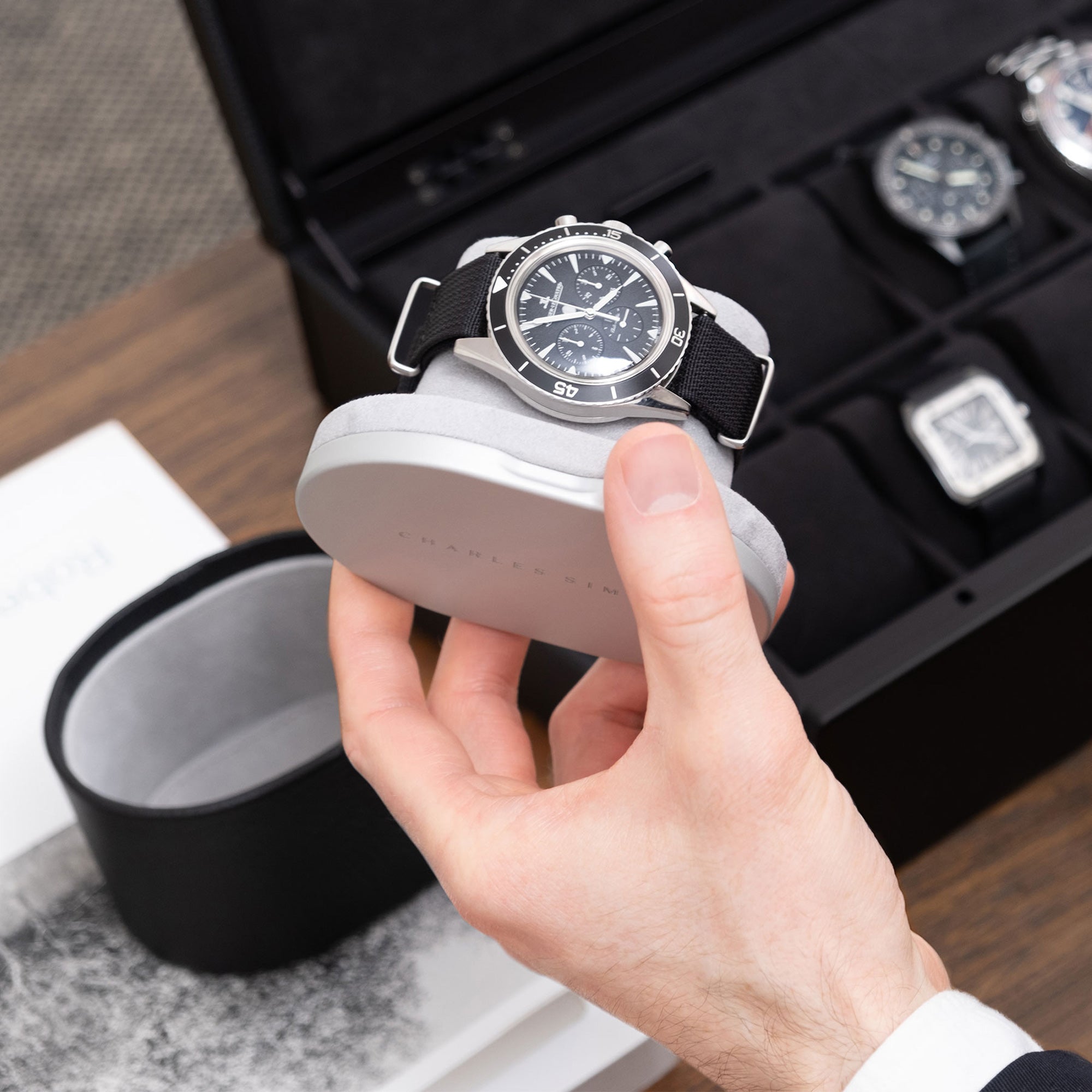Lifestyle shot of open designer Theo single watch roll holding luxury watch on fog grey Alcantara watch cushion
