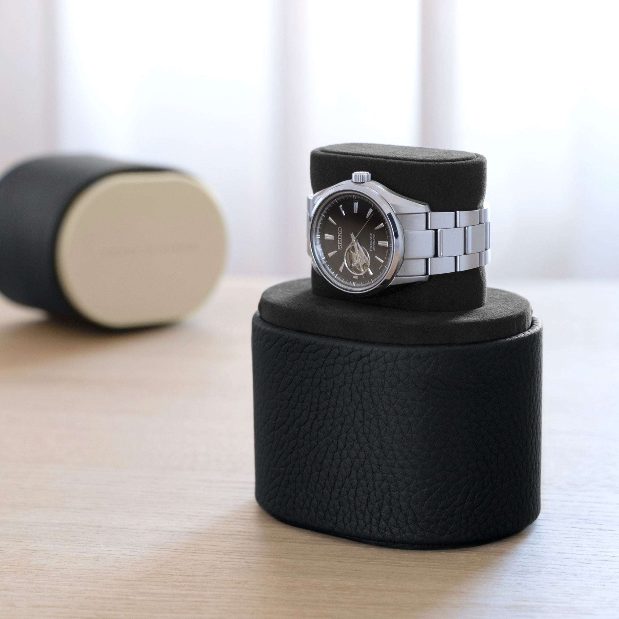 Lifestyle photo showcasing Seiko Watch placed on black leather Theo Watch roll in watch stand position