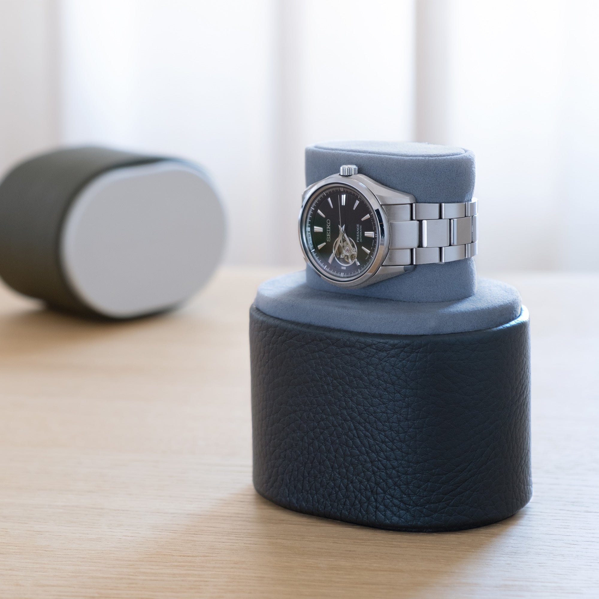 Lifestyle shot of open marine leather Theo watch roll in convenient portable watch stand position holding one watch