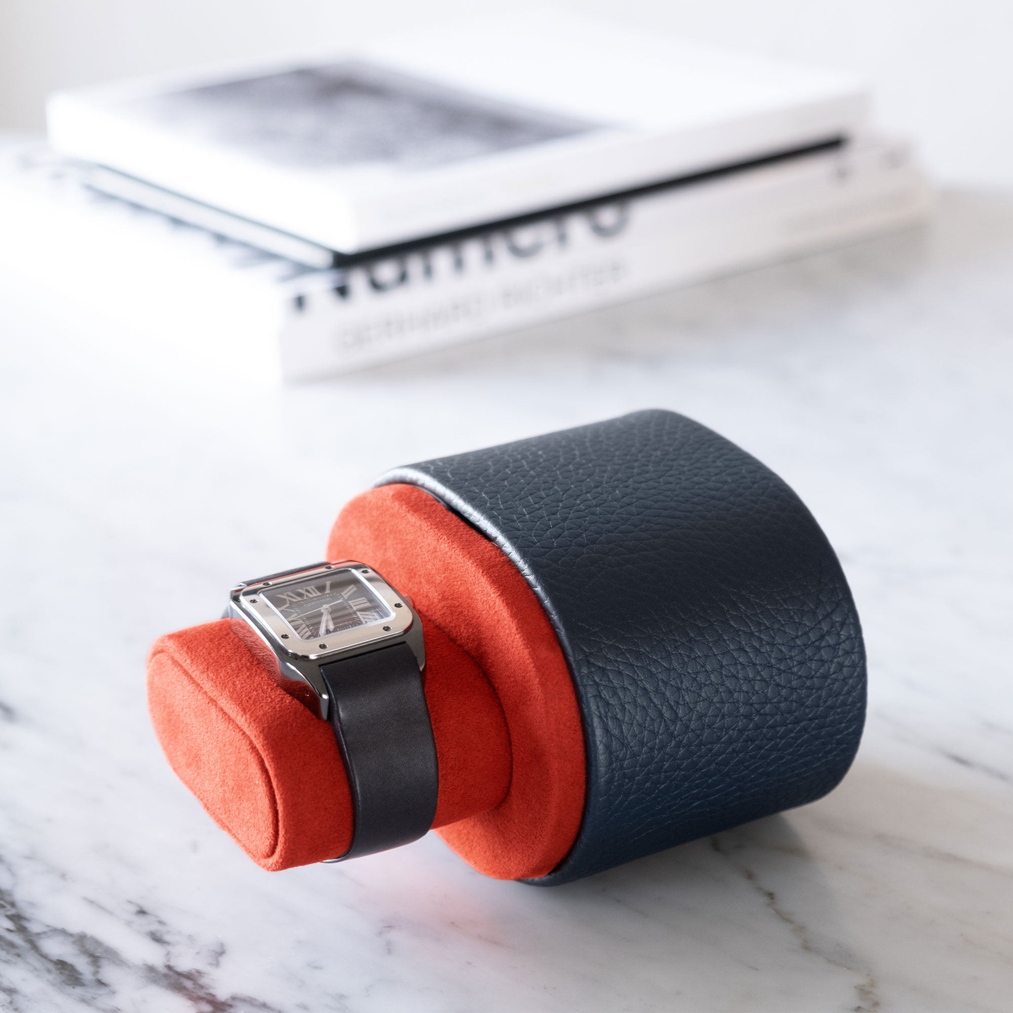 Lifestyle shot of compact luxury watch roll in marine leather and Vermilion interior holding Cartier luxury watch