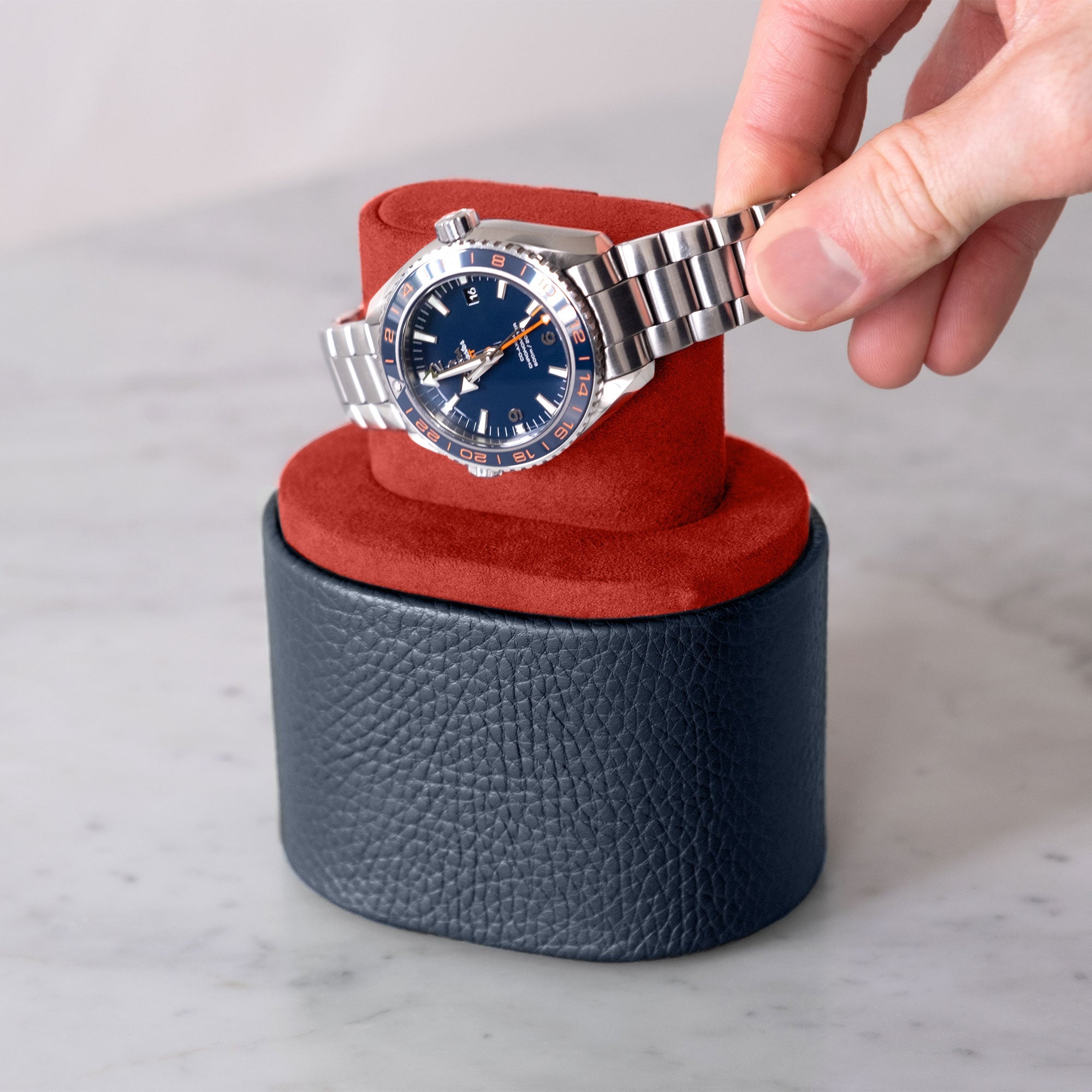 Lifestyle shot of man taking Omega Seamaster Planet Ocean 600M Good Planet luxury watch from vibrant Vermilion Alcantara interior of the designer Theo watch roll by Charles Simon