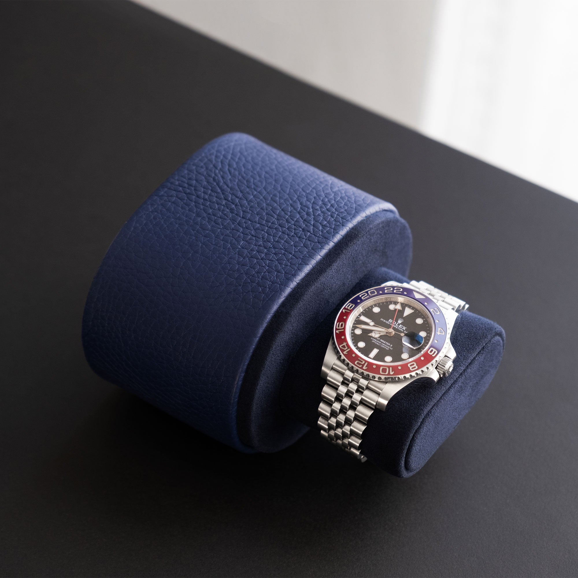 Lifestyle photo of open sapphire leather Theo watch roll for one watch displaying a Rolex Pepsi watch.