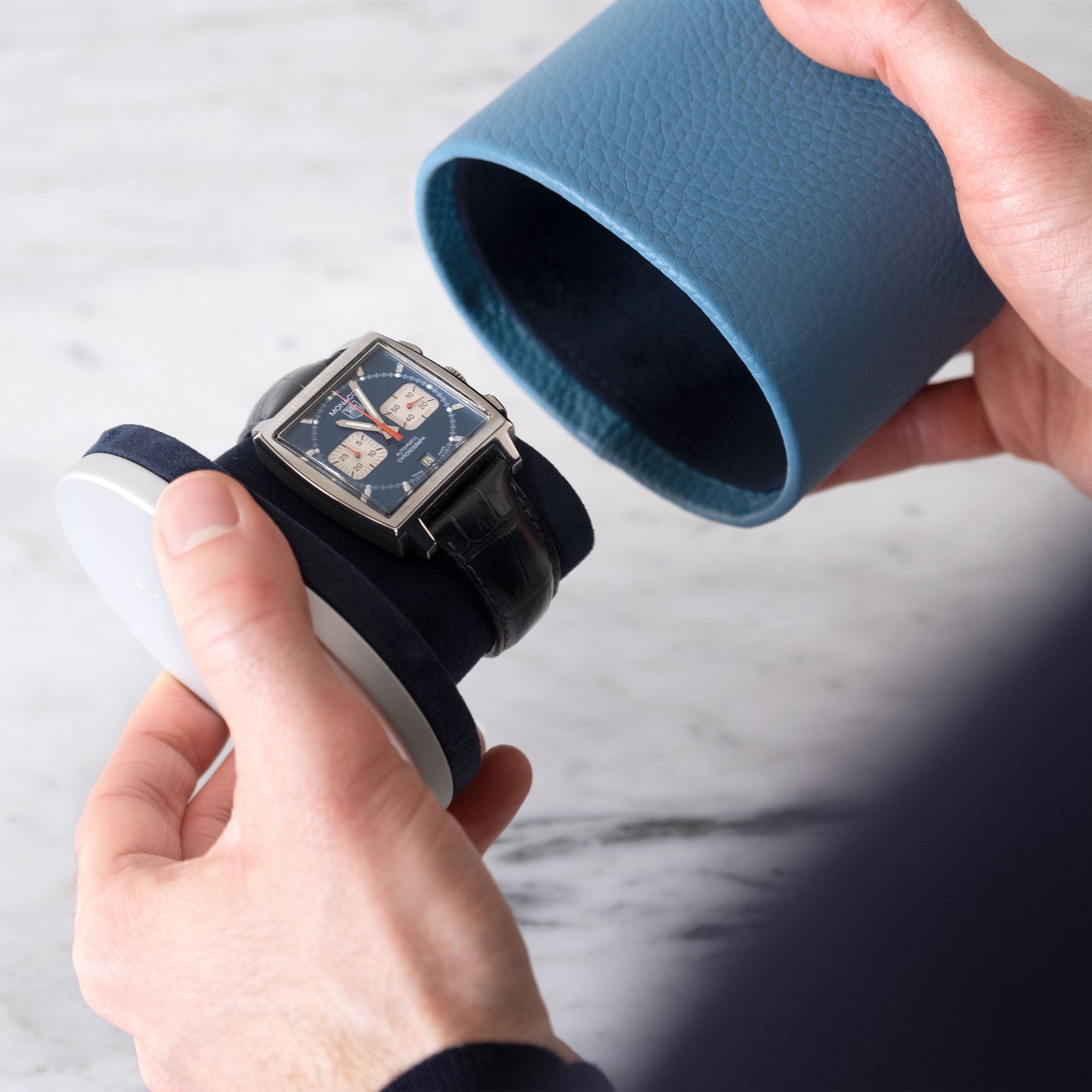 Lifestyle shot of sky blue leather watch roll holding Tag Heuer Monaco luxury watch