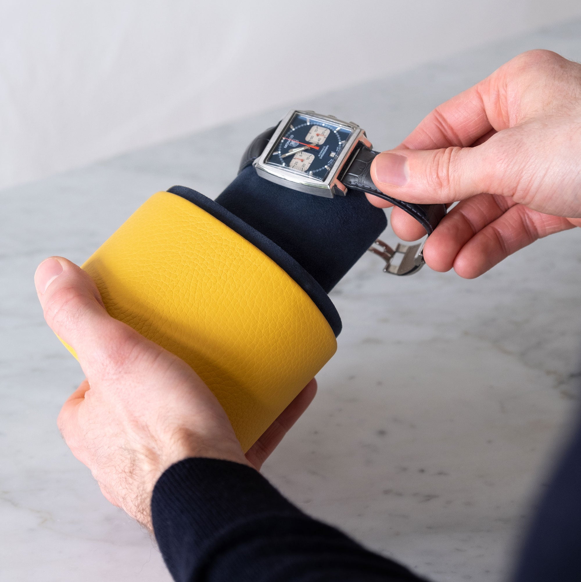 Lifestyle photo of business man putting Tag Heuer Monaco luxury watch on bright sunflower Theo watch roll