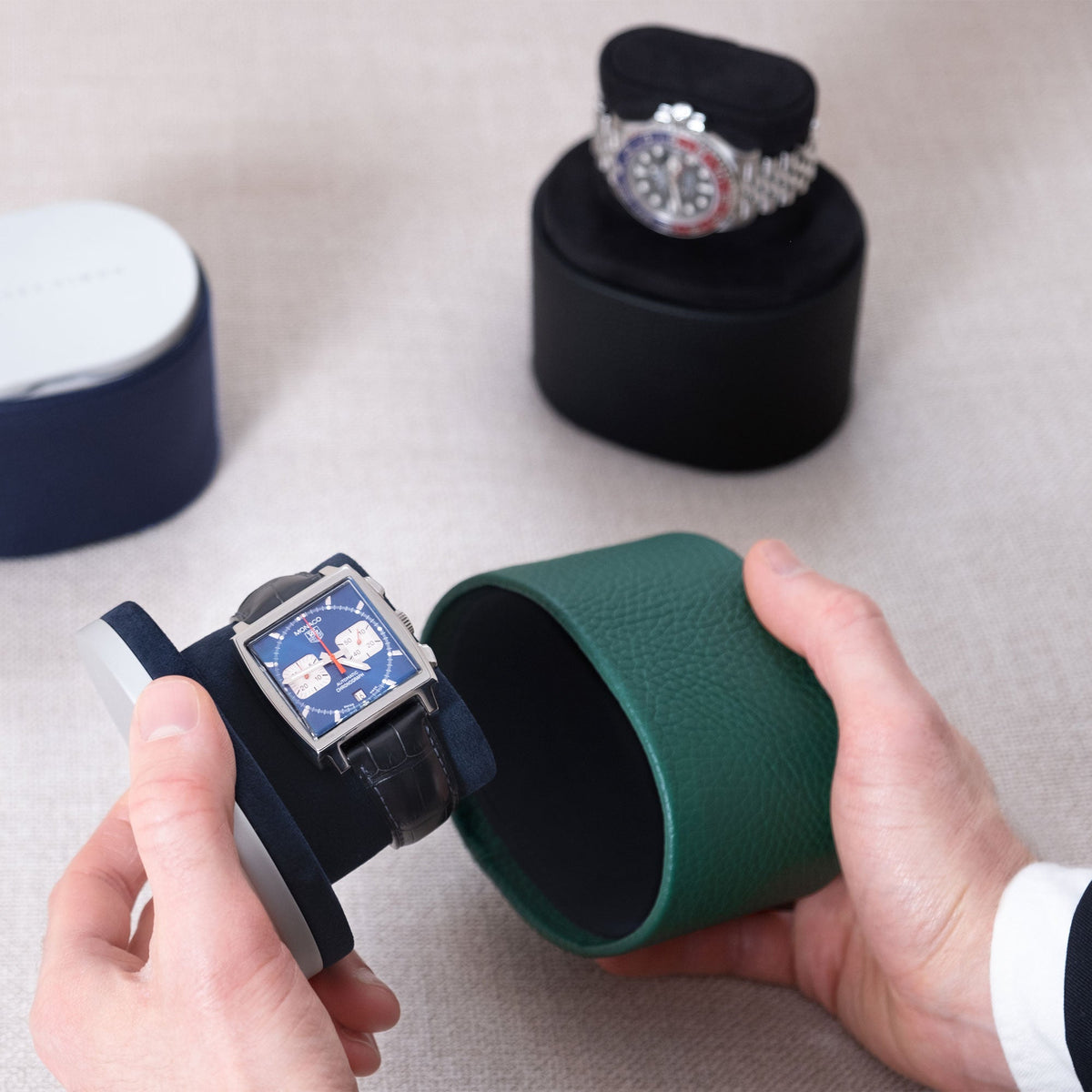 Lifestyle photo of open Theo handmade watch roll in emerald leather and deep blue interior holding Tag Heuer Monaco luxury watch