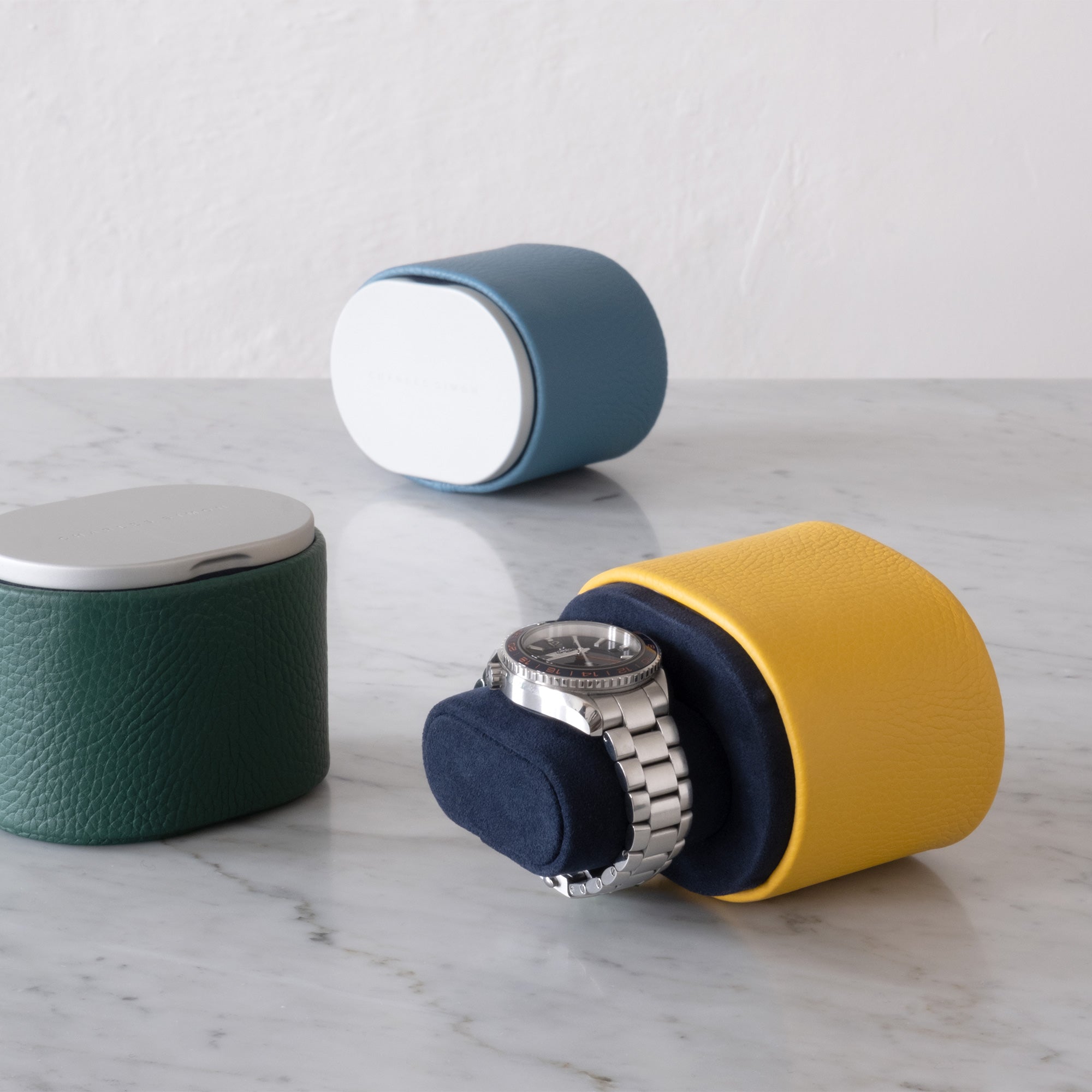 Lifestyle shot of luxury Theo watch rolls by Charles Simon in vibrant leather colors holding one watch