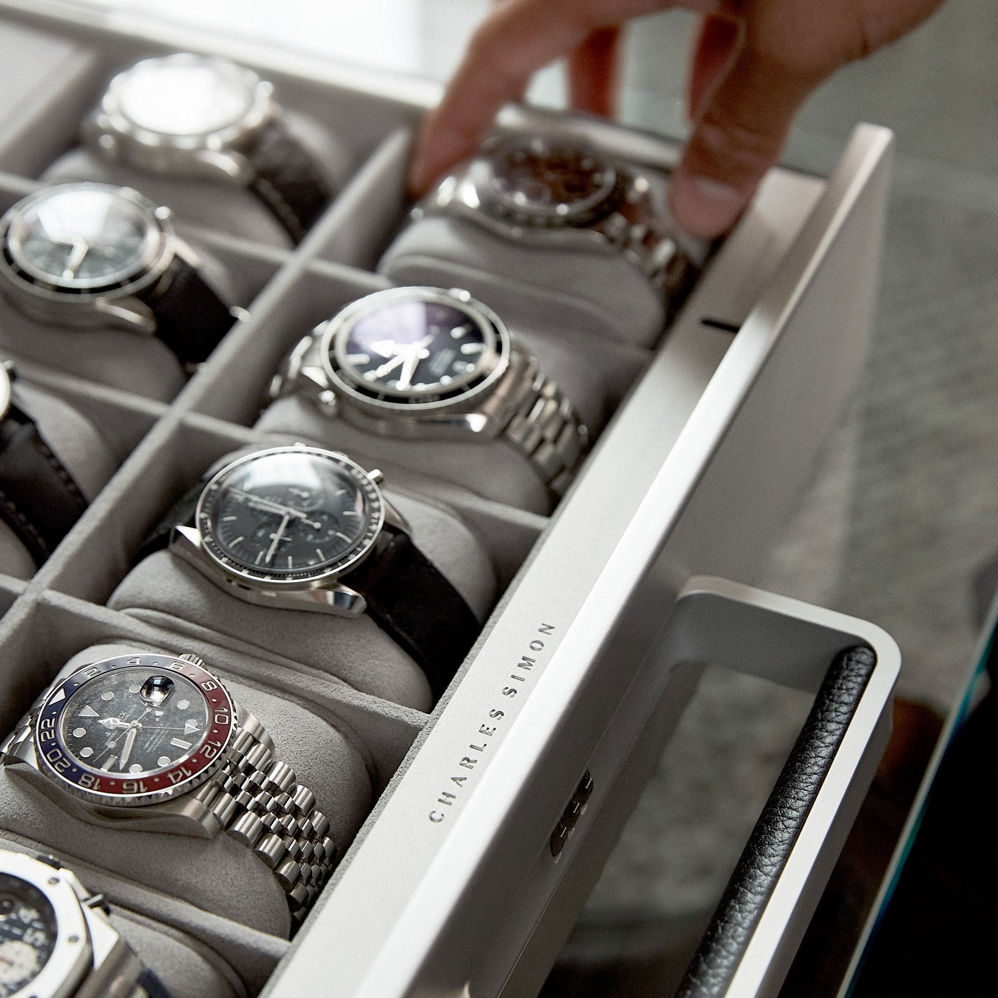 Closeup shot of Charles Simon Mackenzie Watch case featuring aluminum carbon fiber protective casing. The watch case contains luxury watches on removable Alcantara cushions
