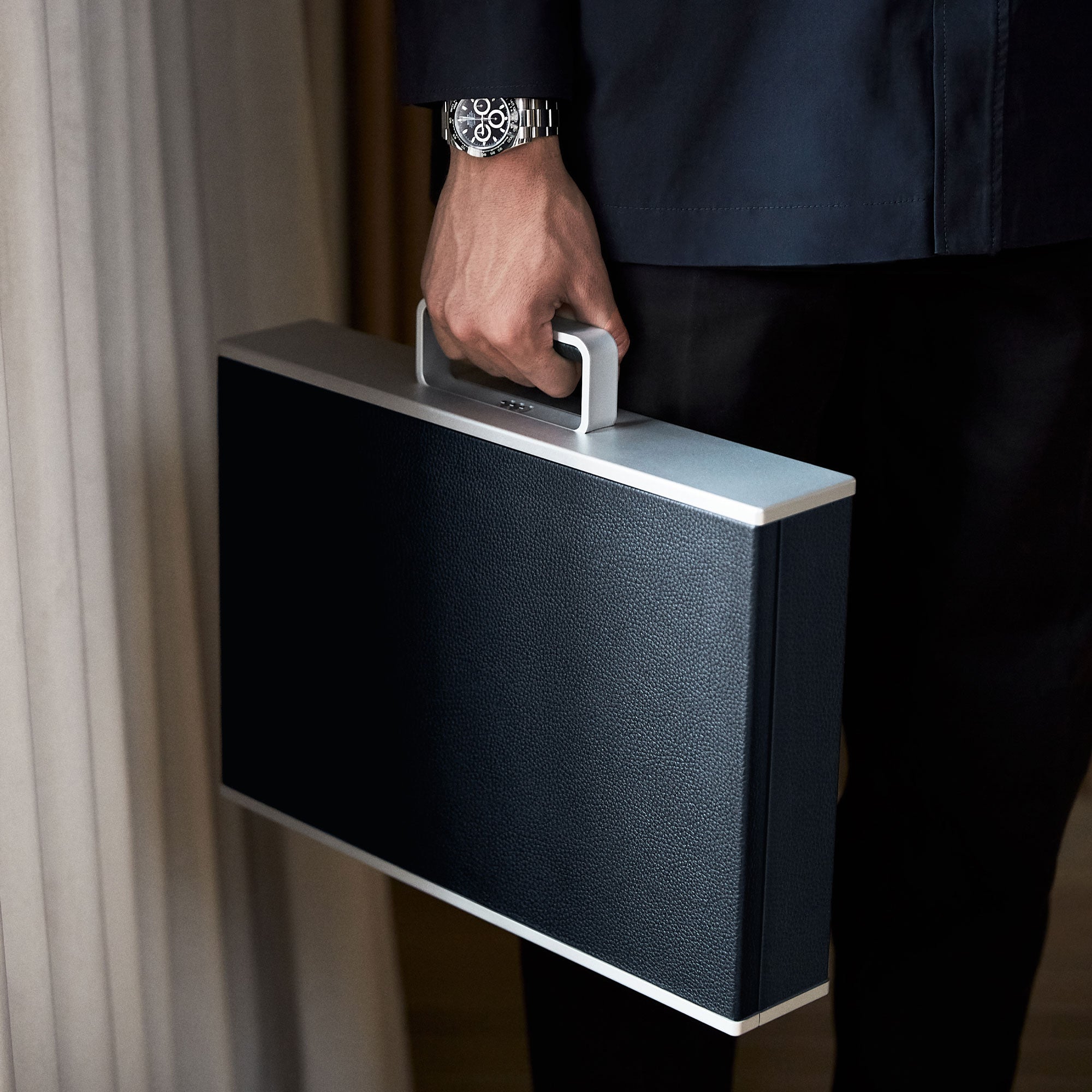Man wearing Rolex watch on wrist while holding marine Mackenzie Watch case made by hand from young bull leather, aluminum carbon fibre and Alcantara interior