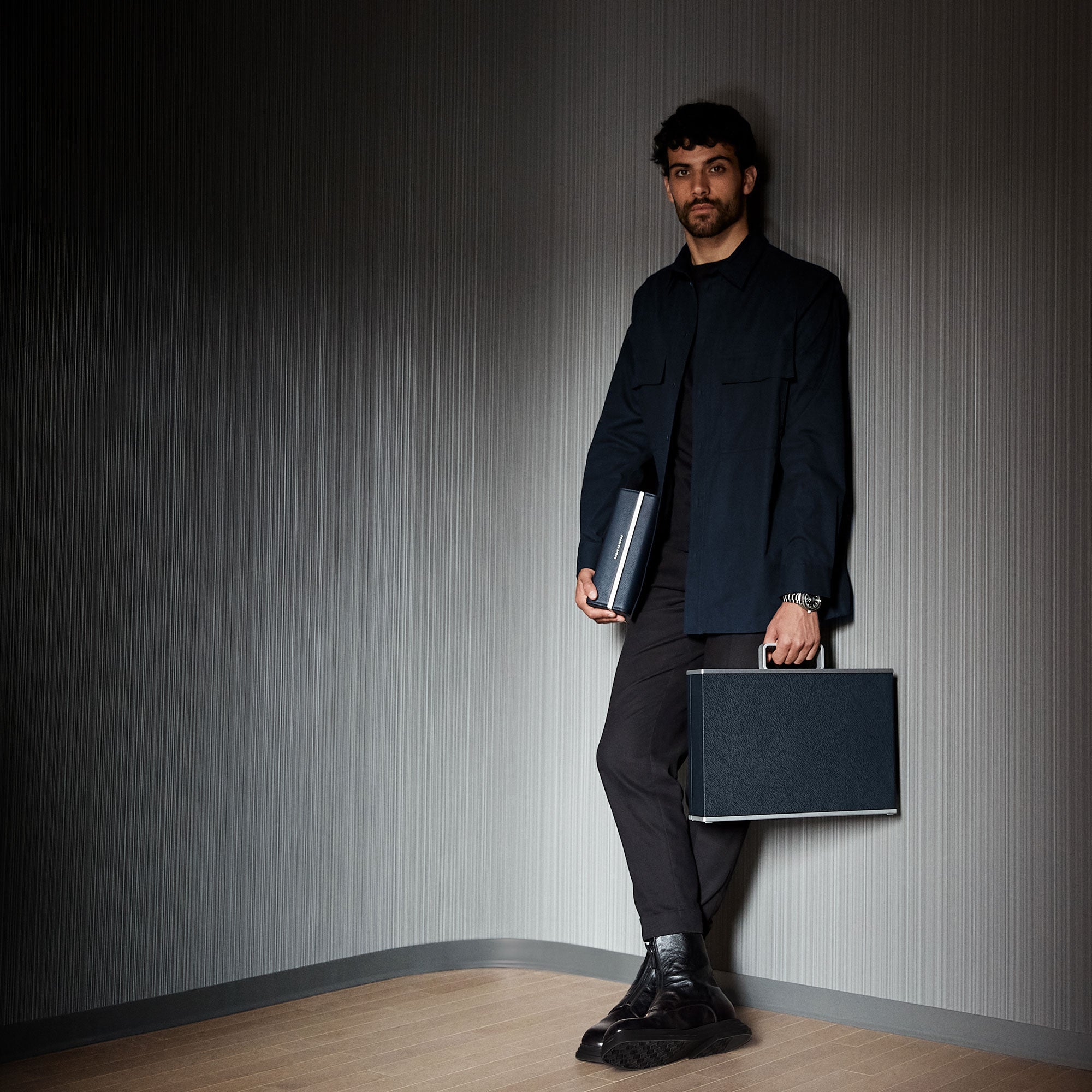 Lifestyle shot of modern watch collector holding marine Eaton watch travel case and black Mackenzie watch case 12