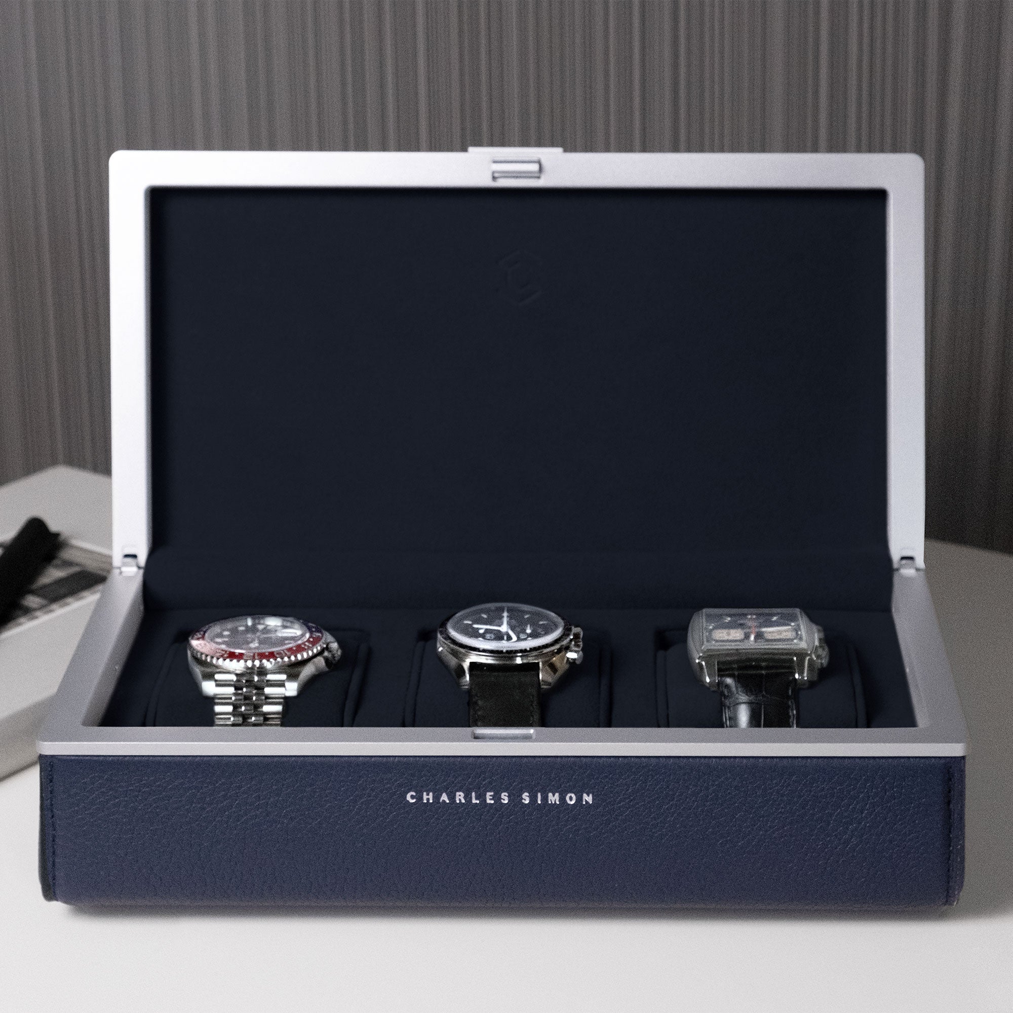 Front view of Eaton 3 watch case in sapphire holding three luxury men's watches 