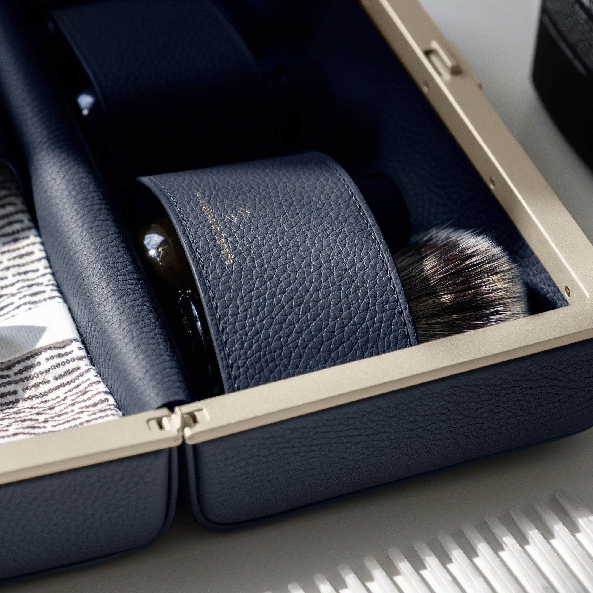 Detail photo of gold casing of the Moraine designer toiletry bag holding a makeup brush and skin care on the road