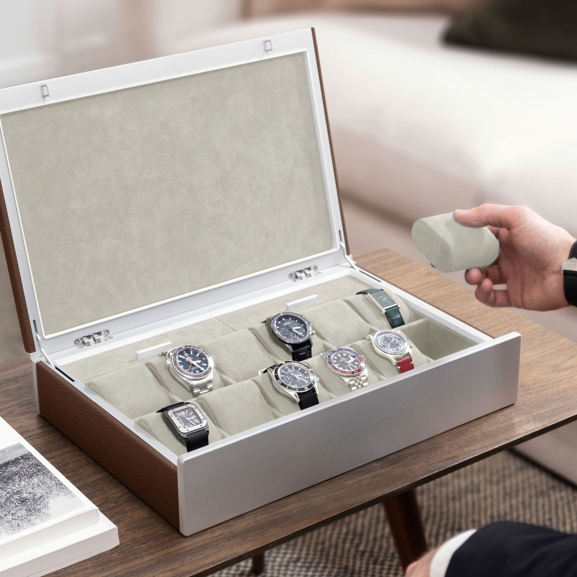Lifestyle photo of man opening tan leather Spence 12 Watch box with luxury watch collection displayed inside