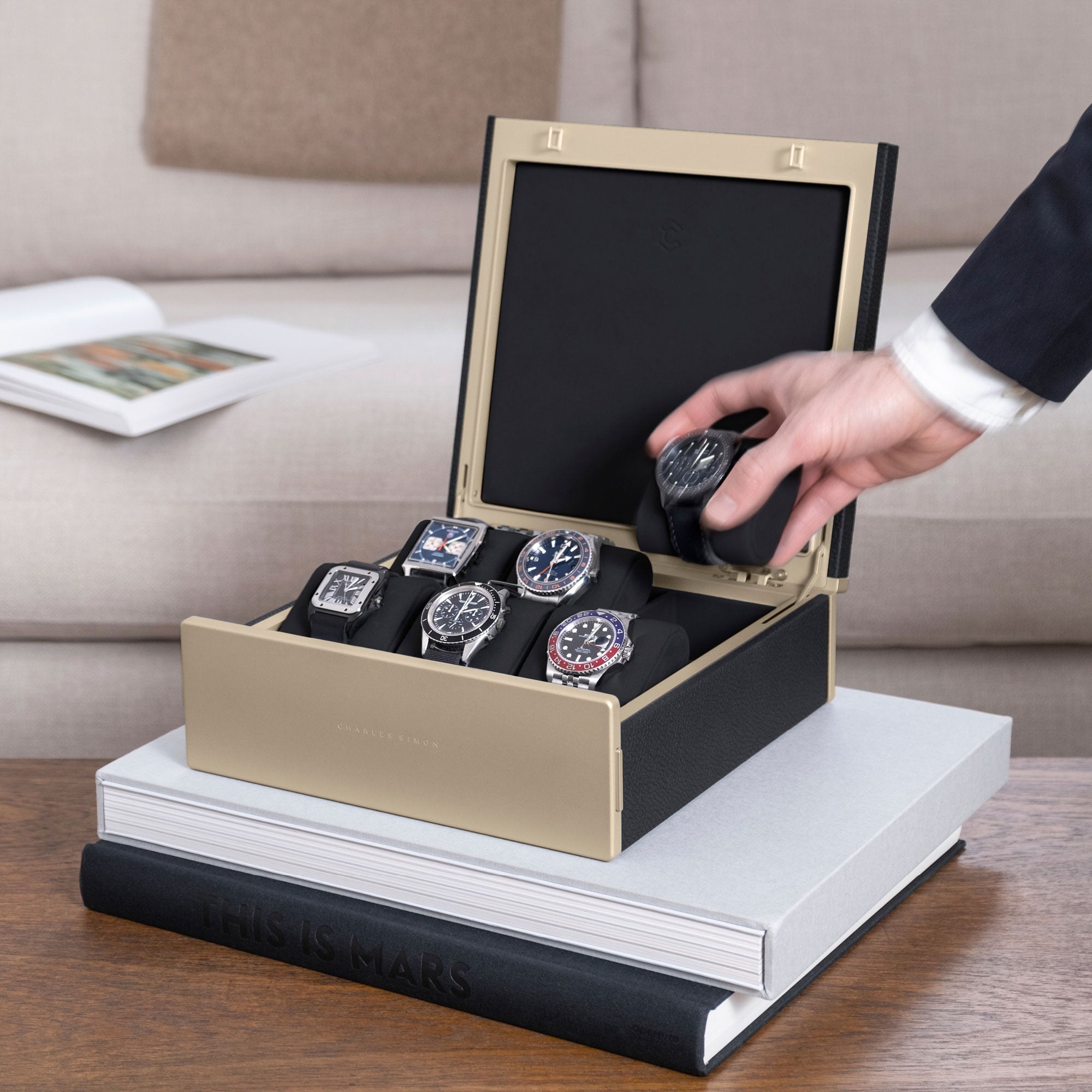 Lifestyle photo of man taking luxury watch from his gold Spence watch box in black leather, holding his watch collection of 6 watches