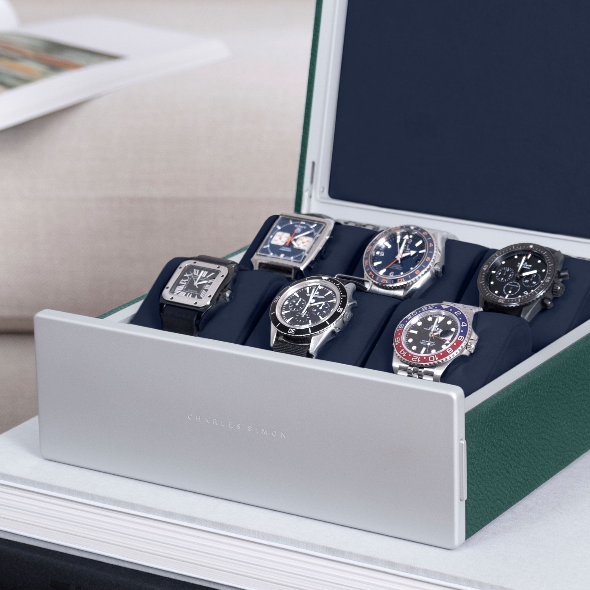 Detail photo of watch collection of six watches, including Cartier, Rolex, Tagheuer, Omega and Jaeger LeCoultre showcased in Spence 6 watch box in emerald leather and deep blue interior