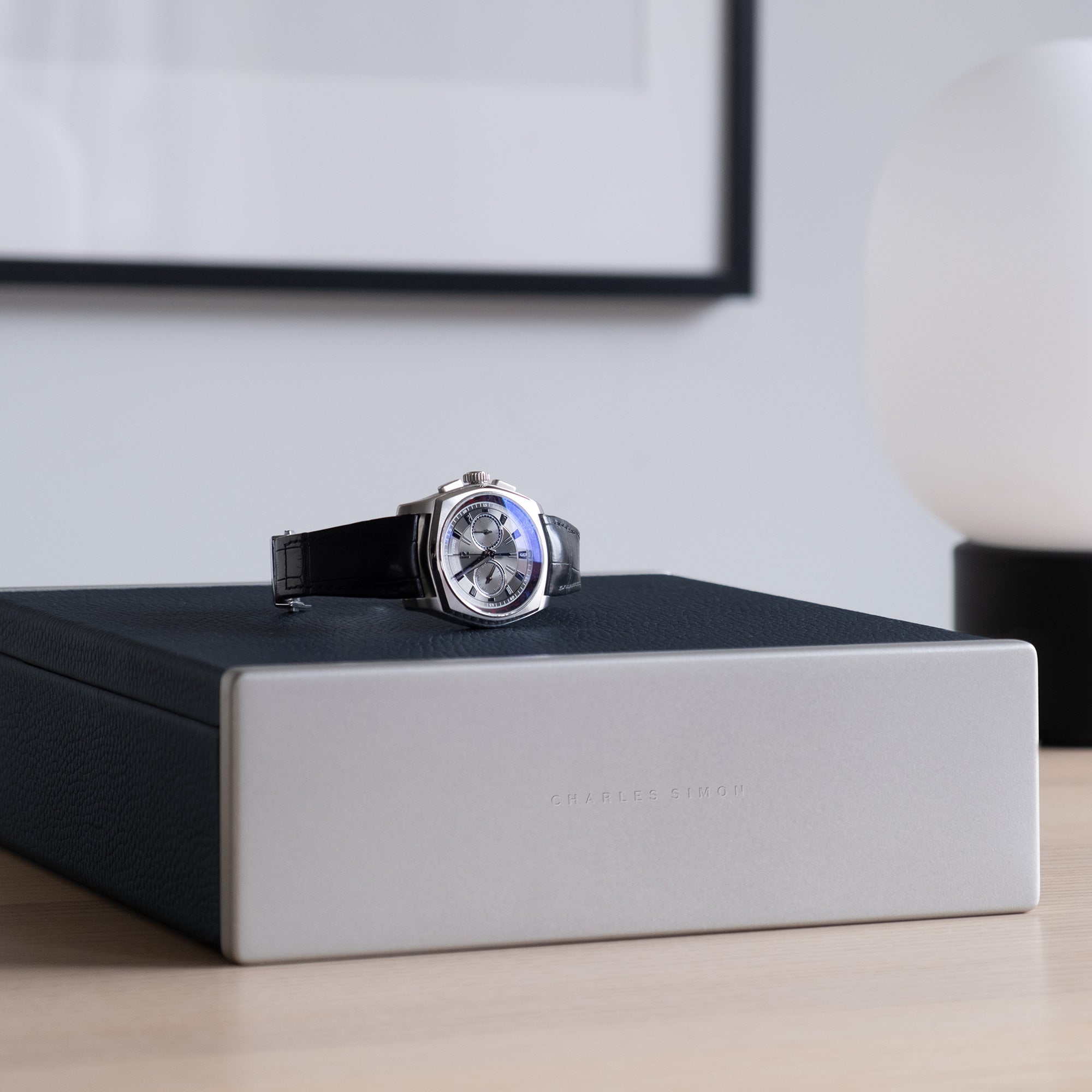 Luxury men's watch placed on top of marine leather Spence watch box in modern apartment