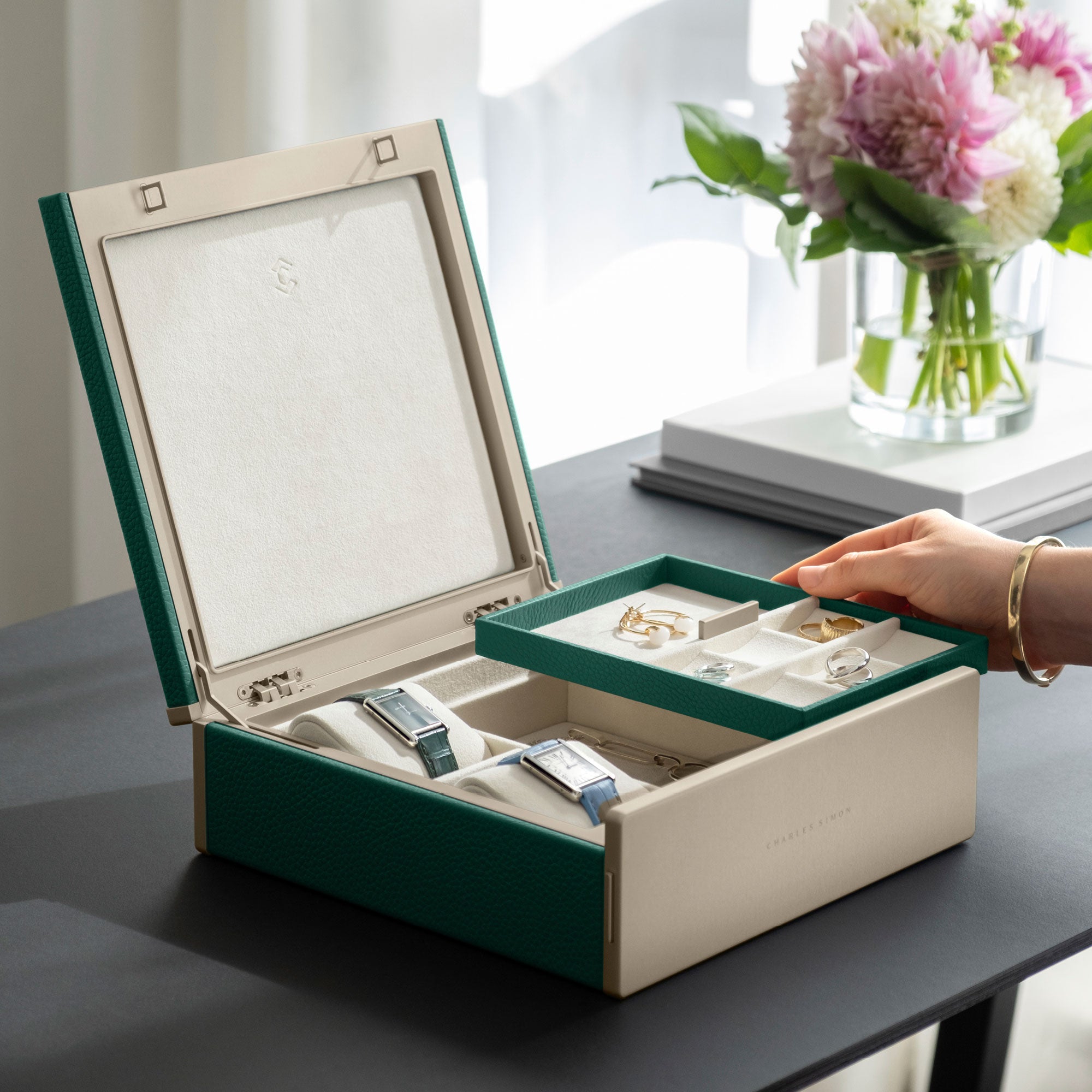 Woman holding jewelry tray from her gold luxury watch and jewelry box. The tray is organizing her rings, earrings, bracelets and necklaces. The box also holds her two watches.