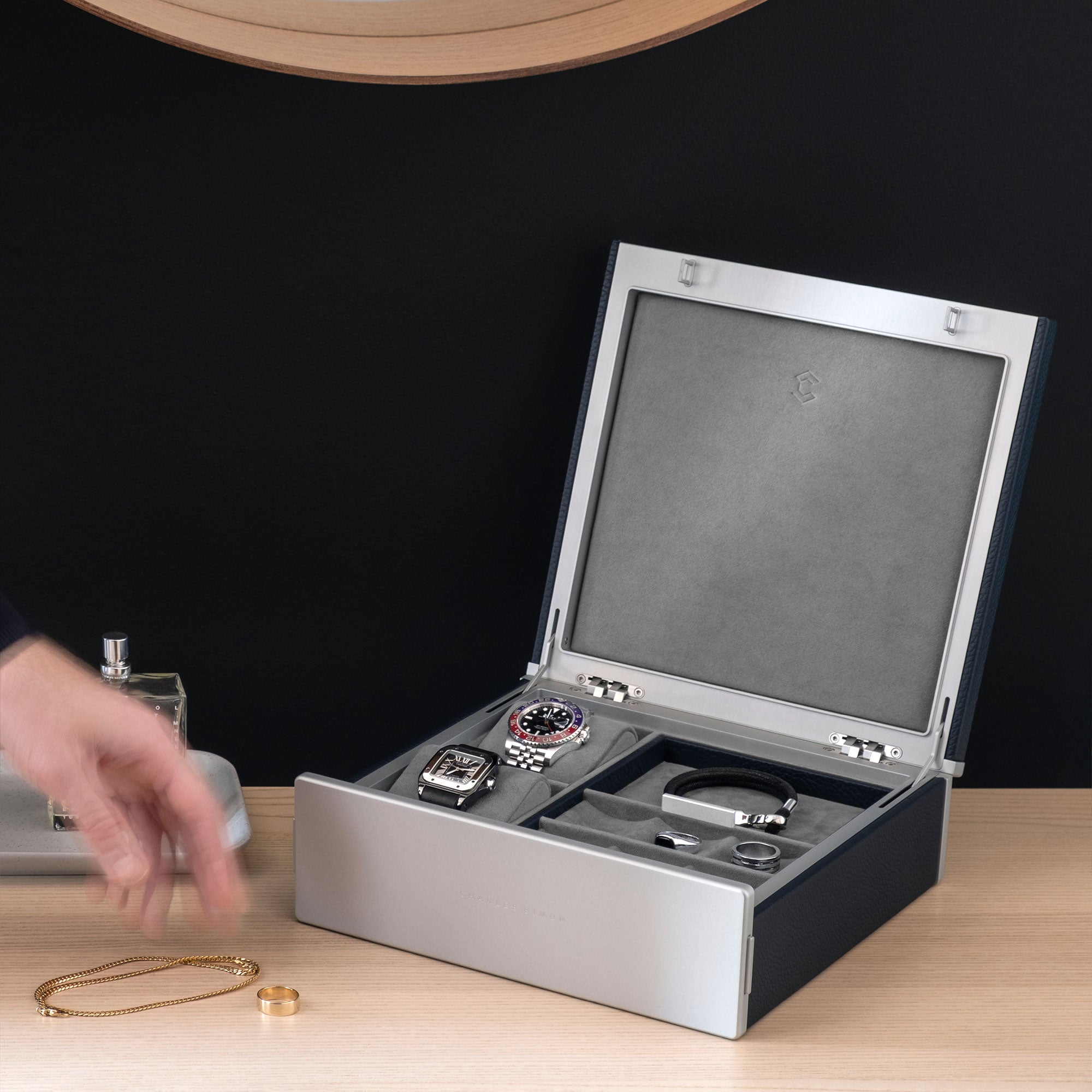 Man reaching for his gold jewelry with his collection of watches and jewelry displayed in his Taylor 2 Watch and Jewelry box in marine. Handmade in Canada.