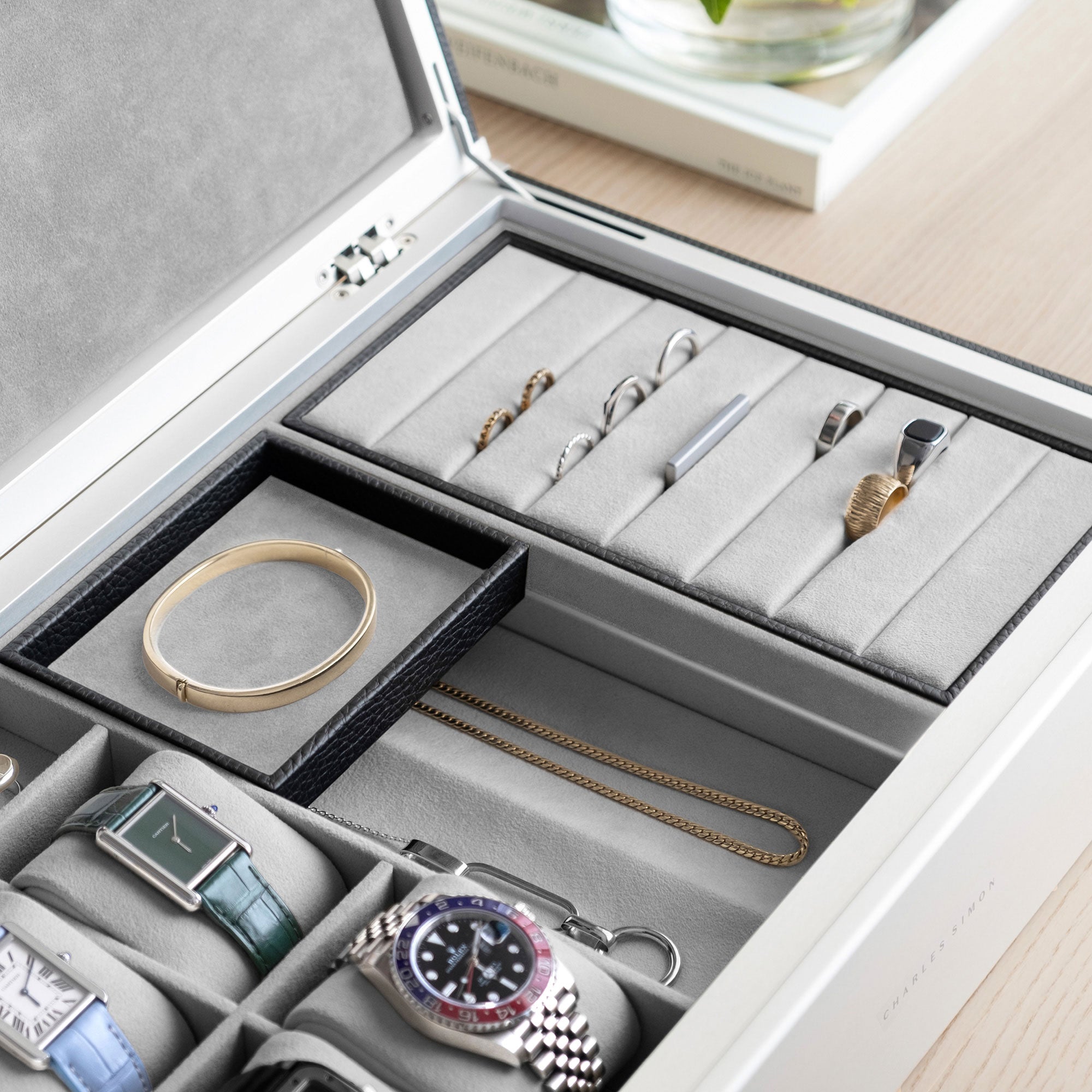 Detail photo of man holding mobile jewelry tray containing a gold bracelet from the black leather and fog grey interior Taylor 4 Watch and Jewelry box. The Taylor 4 Watch and Jewelry box is storing 4 luxury watches and a collection of fine jewelry, including gold and silver rings, earrings, bracelets and necklaces.